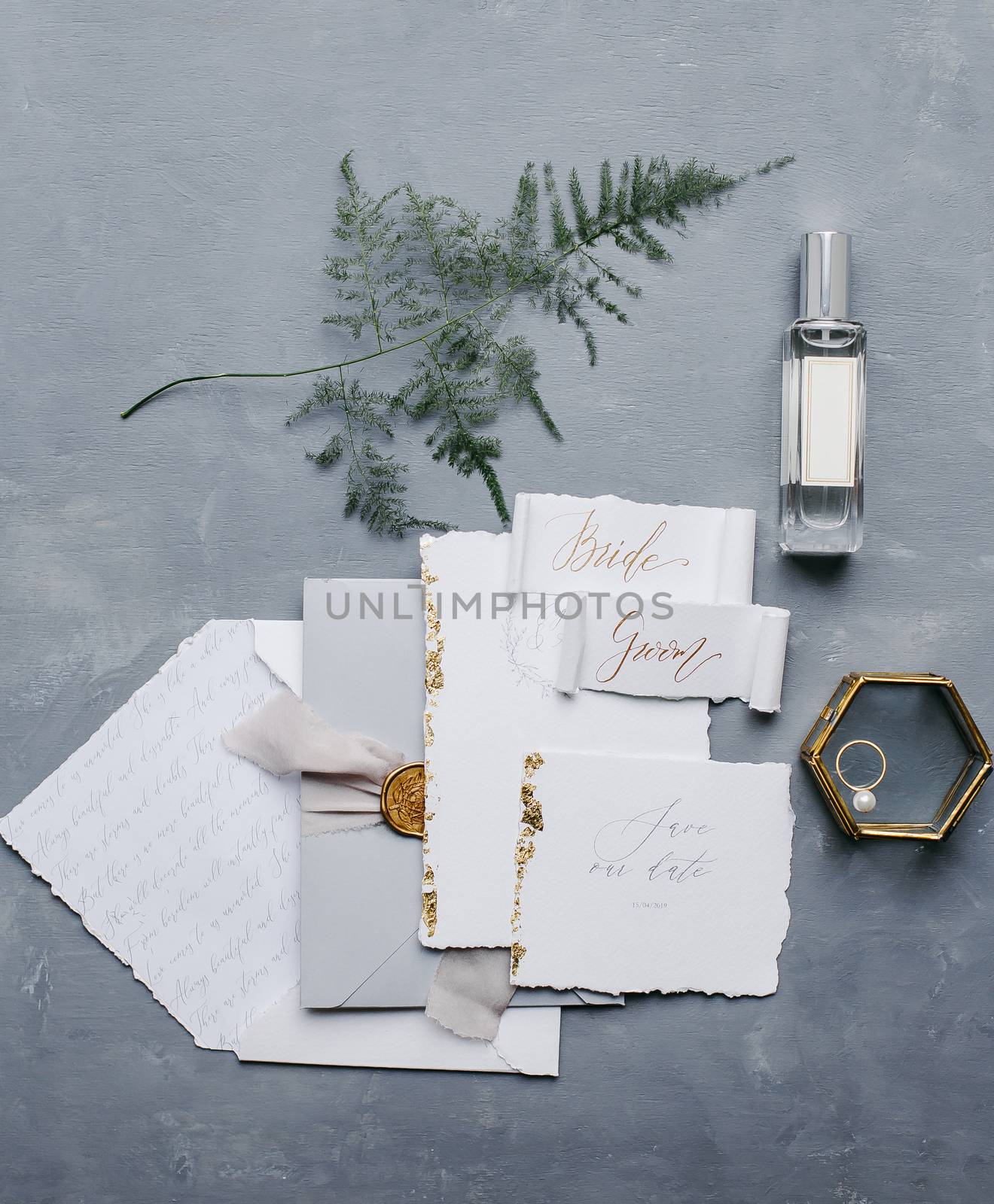 Wedding details flat lay. Wedding invitation and scroll paper. Bottle with fragrance. Simple bouquet. Ring box.