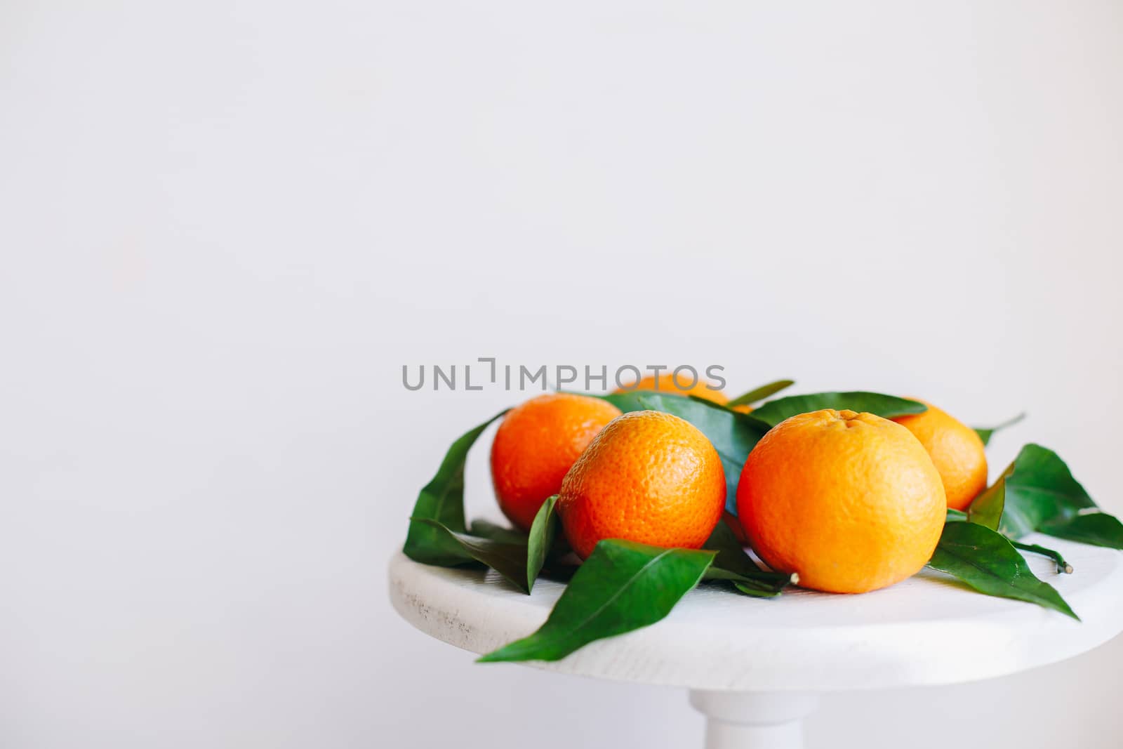 Orange tangerines on grey background in New Year's decor with brown pine cones and green leaves. Delicious sweet clementine. Christmas decoration with mandarins.