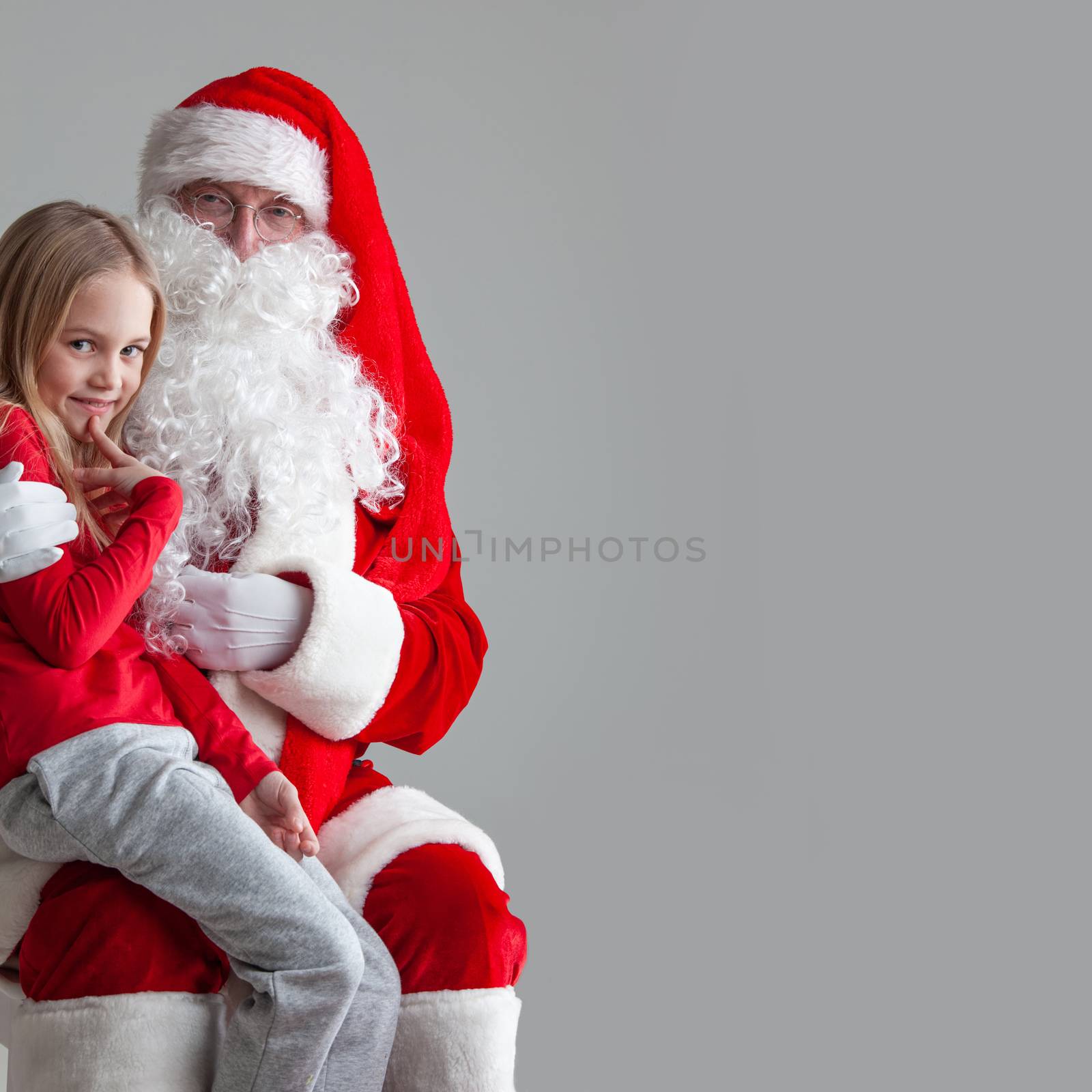 Portrait of smiling little girl sitting on santa claus knees near christmas tree