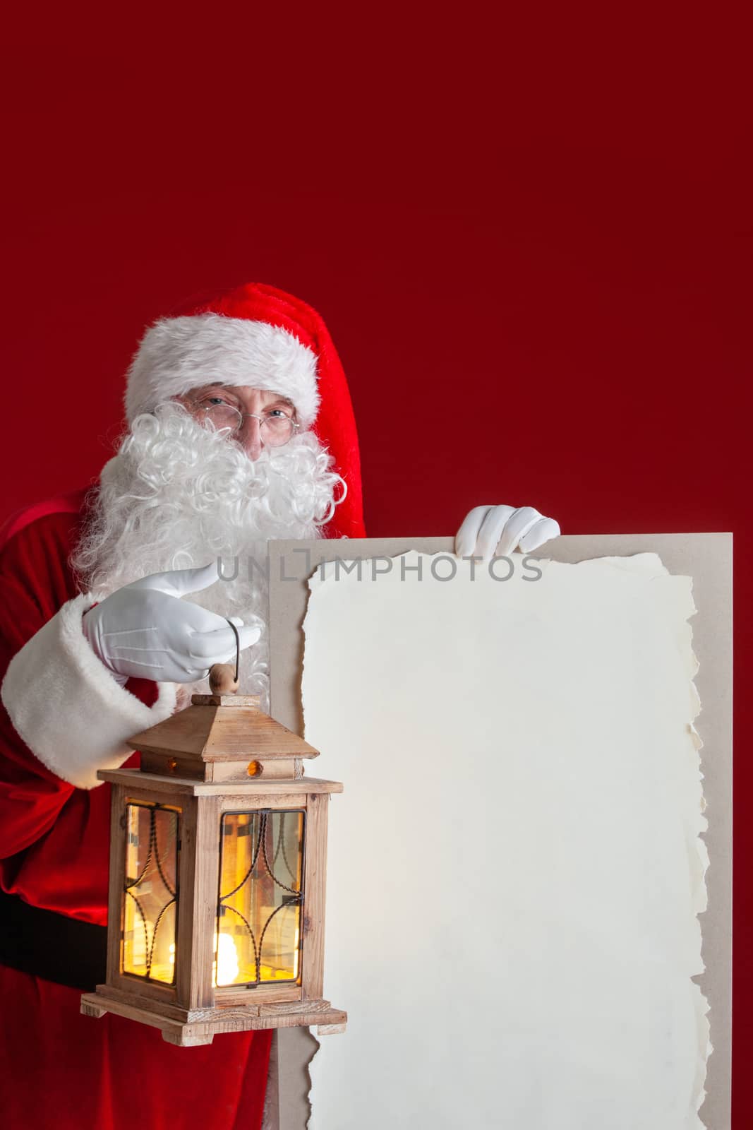 Santa Claus with lantern holding vintage paper billboard with copy space for text