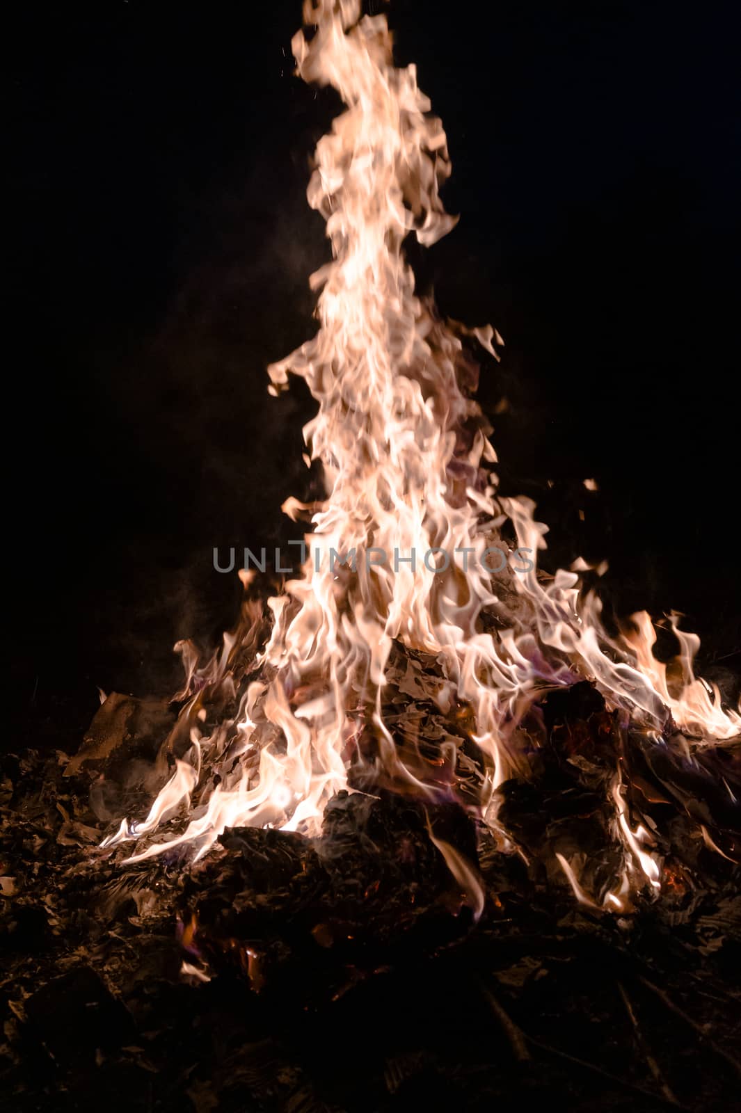 A low light underexposed photo of burning fire. Many sparks and flames. Burning books and wood. 