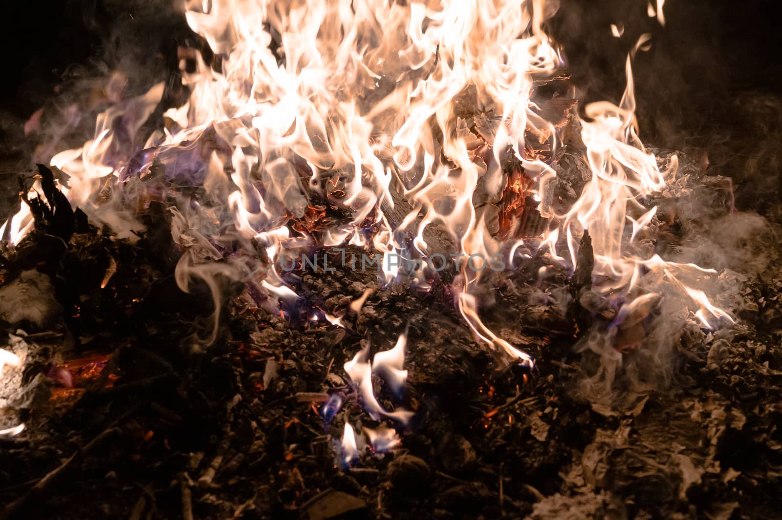 A low light underexposed photo of burning fire. Many sparks and flames. Burning books and wood. 