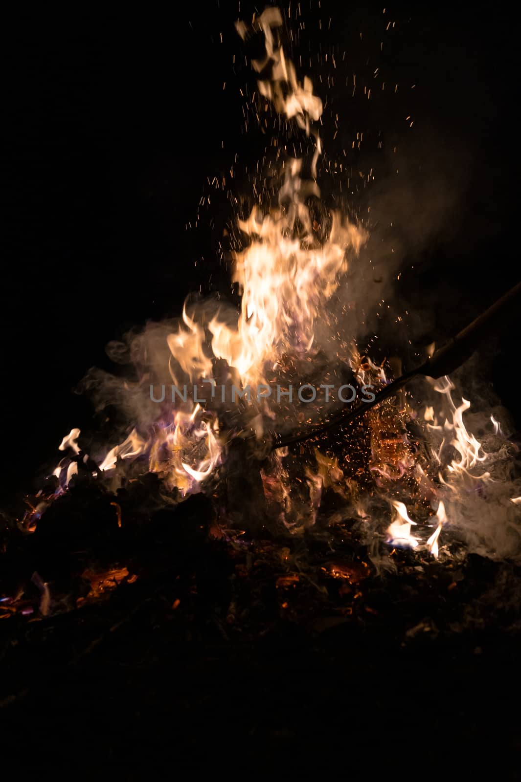 A low light underexposed photo of burning fire. Many sparks and flames. Burning books and wood. 