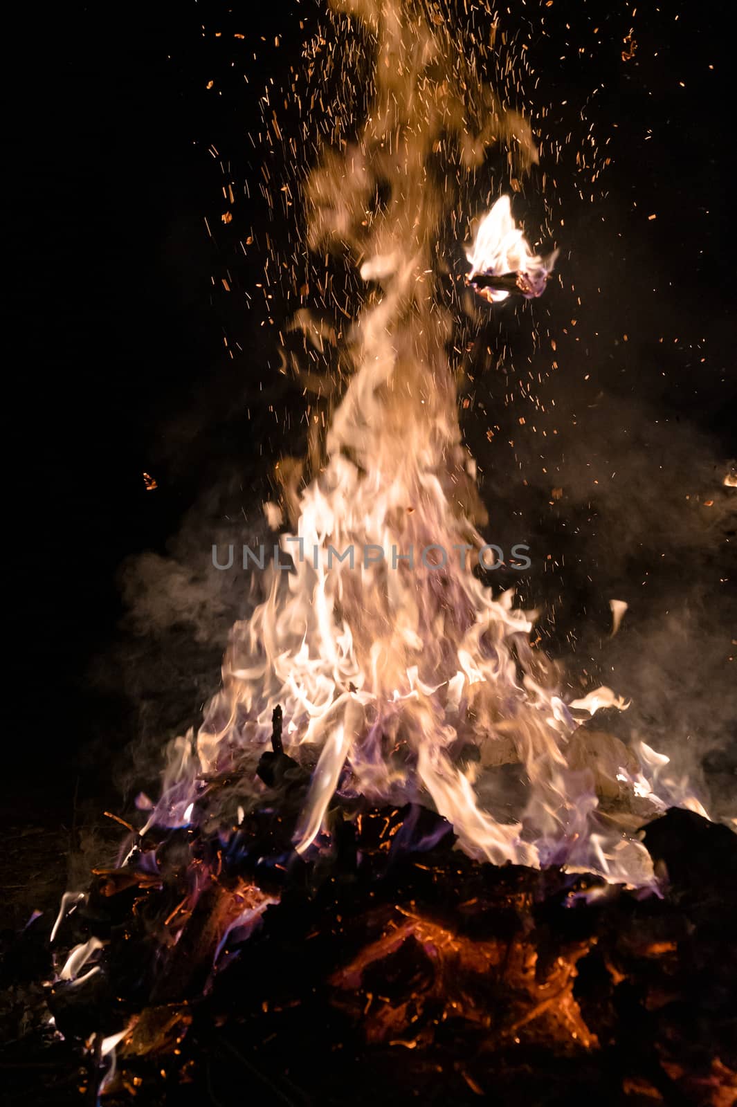 A low light underexposed photo of burning fire. Many sparks and flames. Burning books and wood. 