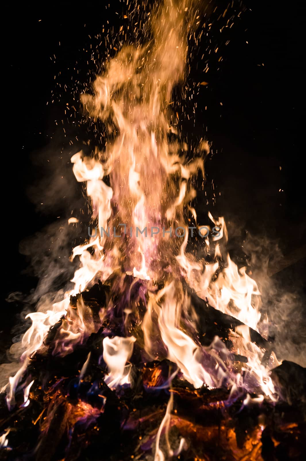 A low light underexposed photo of burning fire. Many sparks and flames. Burning books and wood. 