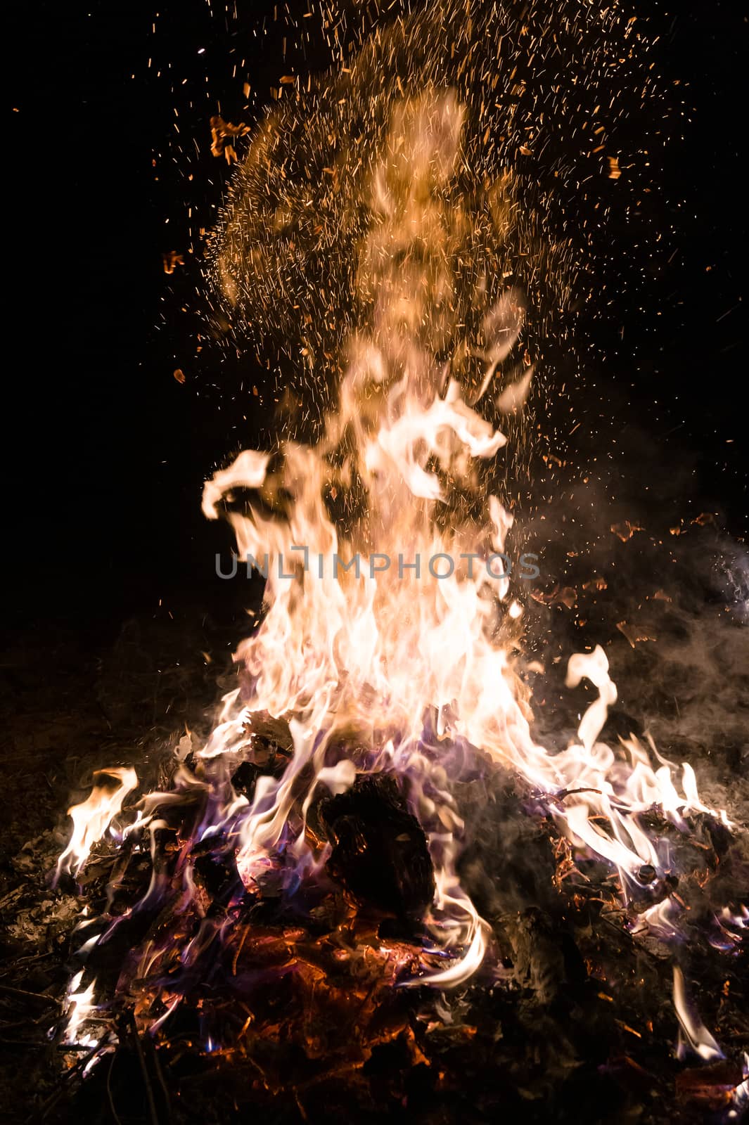 A low light underexposed photo of burning fire. Many sparks and flames. Burning books and wood. 