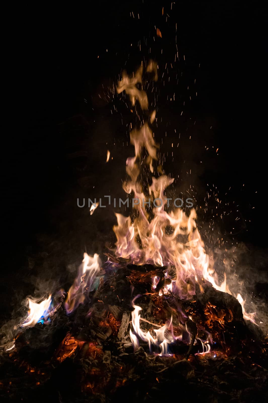 A low light underexposed photo of burning fire. Many sparks and flames. Burning books and wood. 