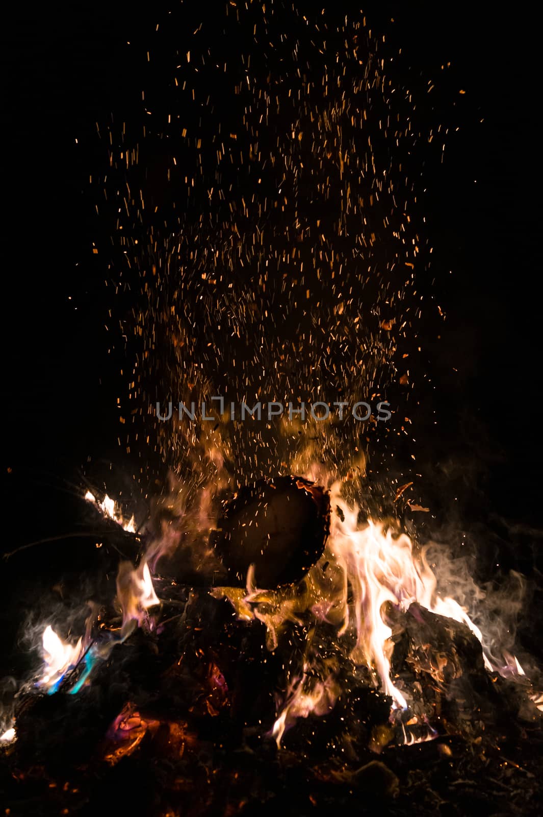 A low light underexposed photo of burning fire. Many sparks and flames. Burning books and wood. 