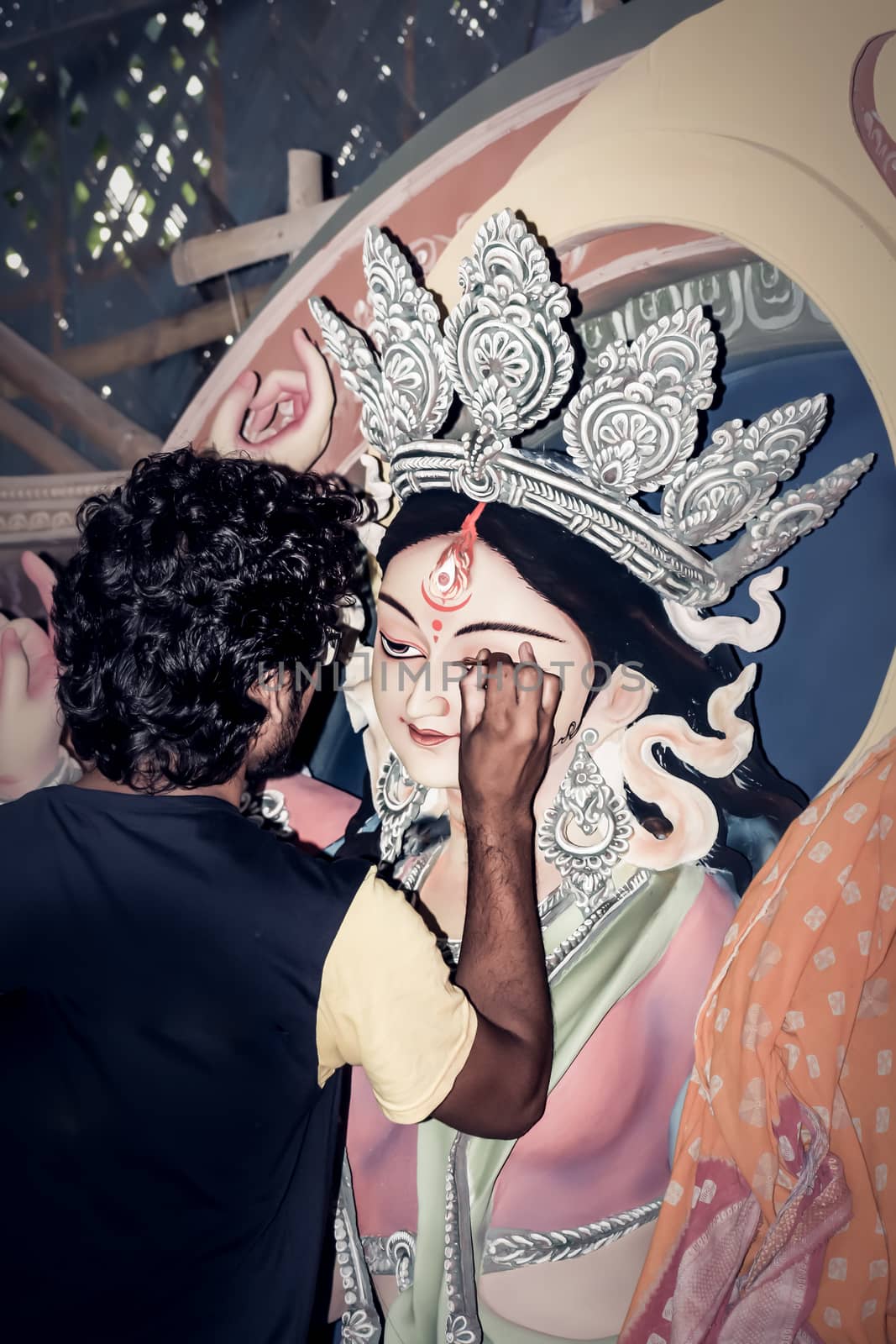 Painting the Eye over clay Idol of Hindu Goddess Durga. An idol making process of Pottery Artist at Kumartuli during Durga Puja Festival. Kolkata. West Bengal, India by sudiptabhowmick