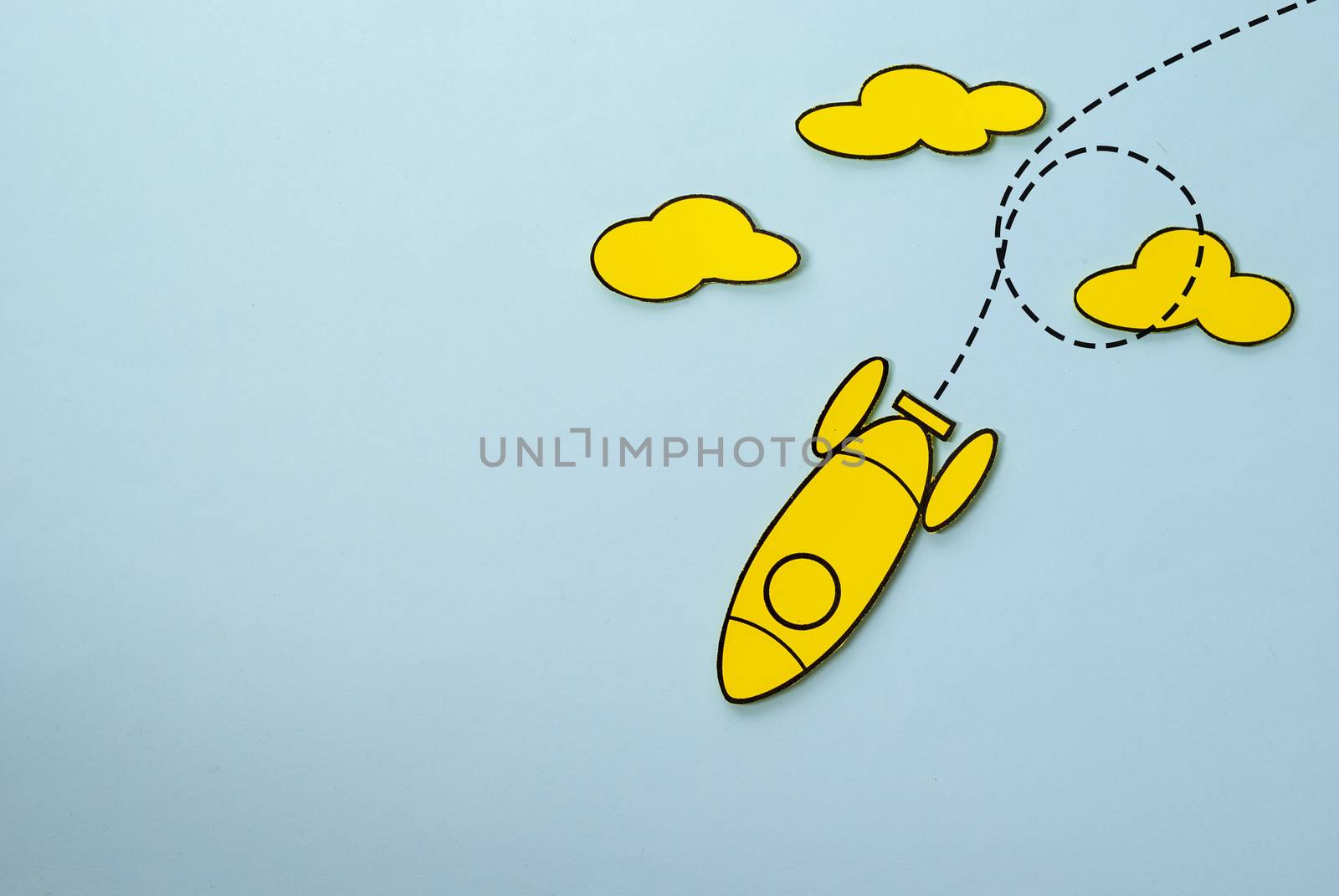 Yellow rocket looping around the clouds in the sky over a blue background with copy space in a conceptual image