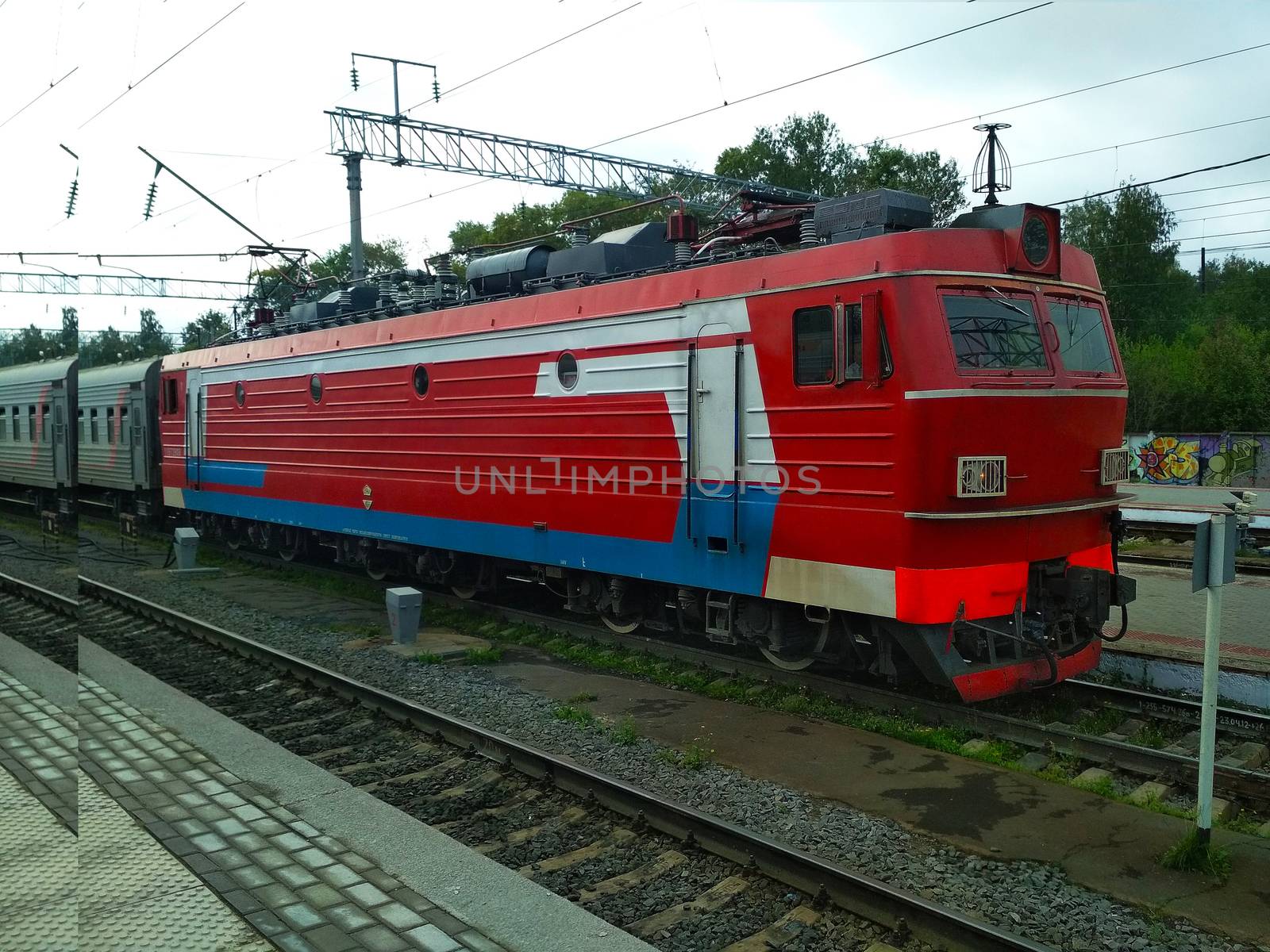 

Modern red train with cars on the railway tracks.