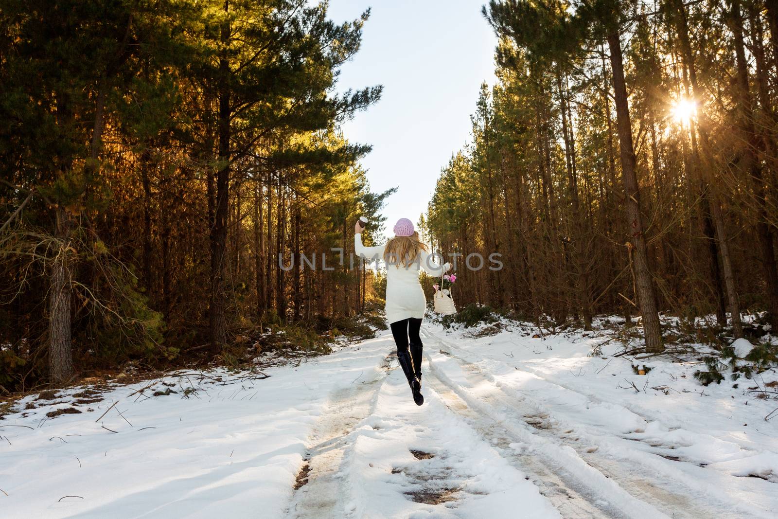 A happy energetic woman frolicks in the snow among the forest trees
