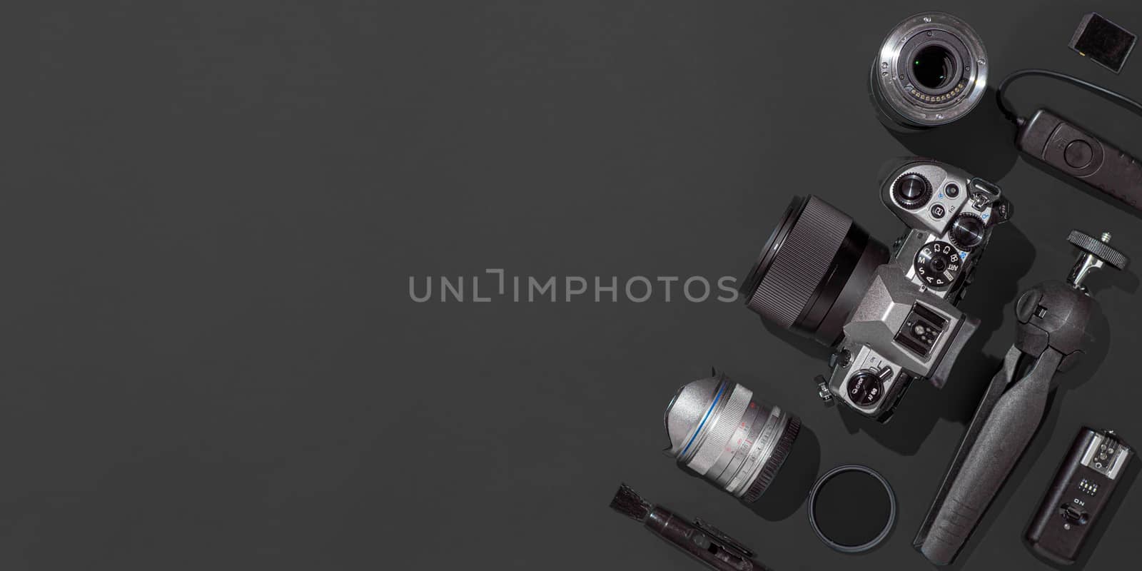 Photographer workplace with dslr camera, lens, pen tablet and camera accessories on black background. Camera, photography, visual content concept. Flat lay or top view. Copy space. Hard light. Banner