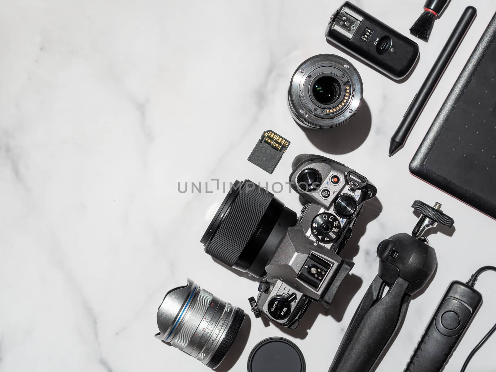 Photographer workplace with dslr camera, lens, pen tablet and camera accessories on white marble background. Camera, photography, visual content concept. Flat lay or top view. Copy space. Hard light.