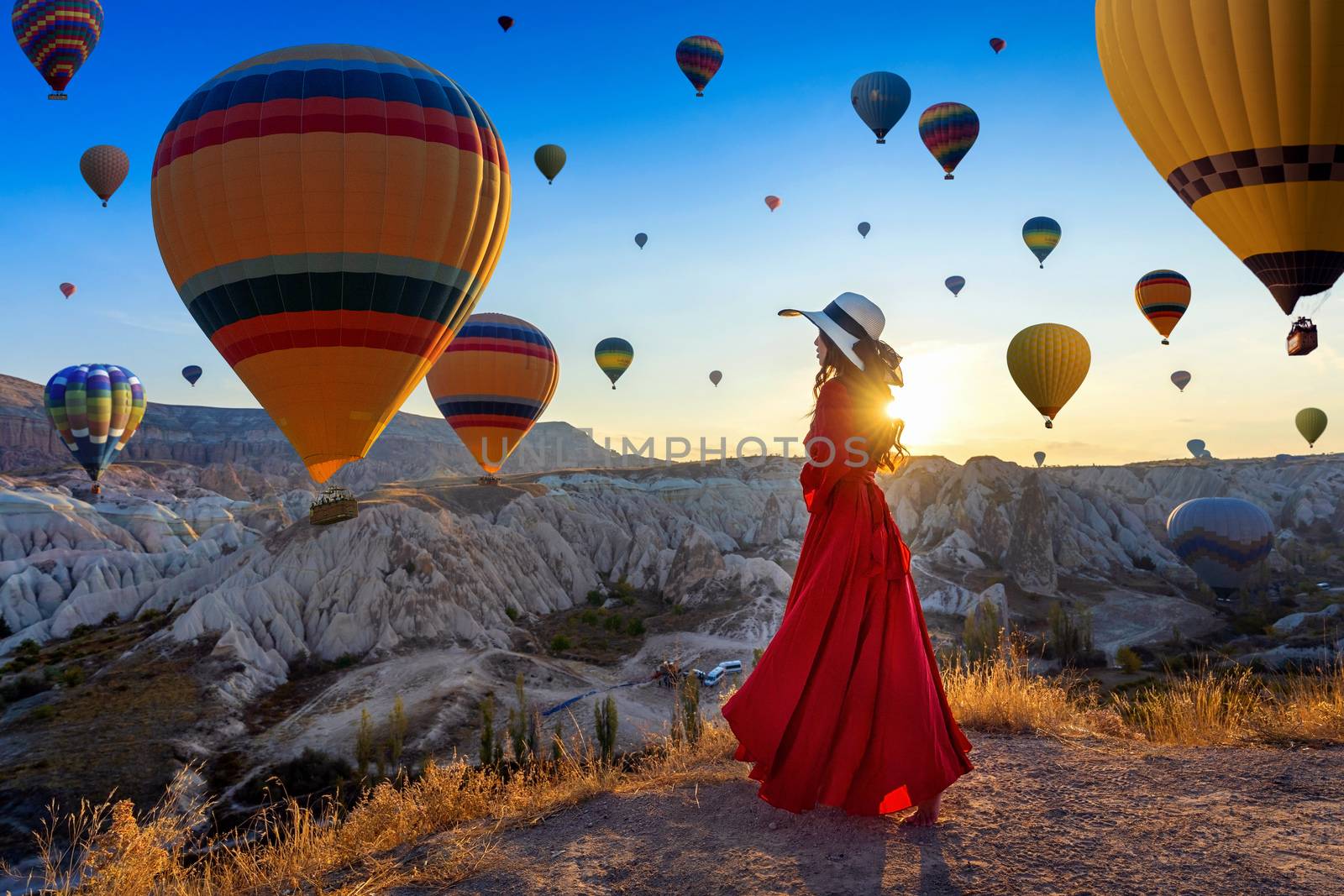 Beautiful girl standing and looking to hot air balloons in Cappadocia, Turkey. by gutarphotoghaphy