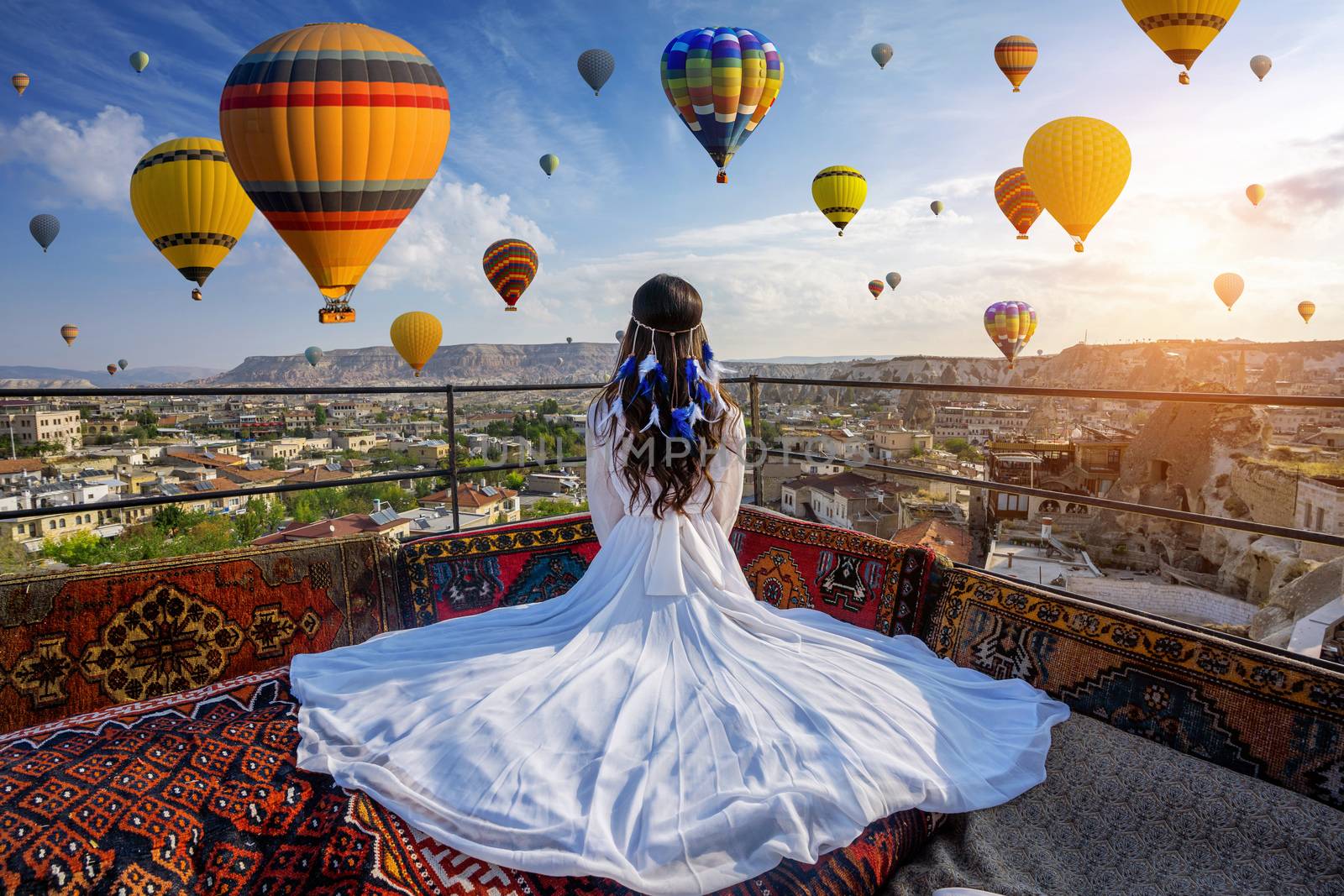 Beautiful girl sitting on the hotel and looking to hot air balloons in Cappadocia, Turkey. by gutarphotoghaphy