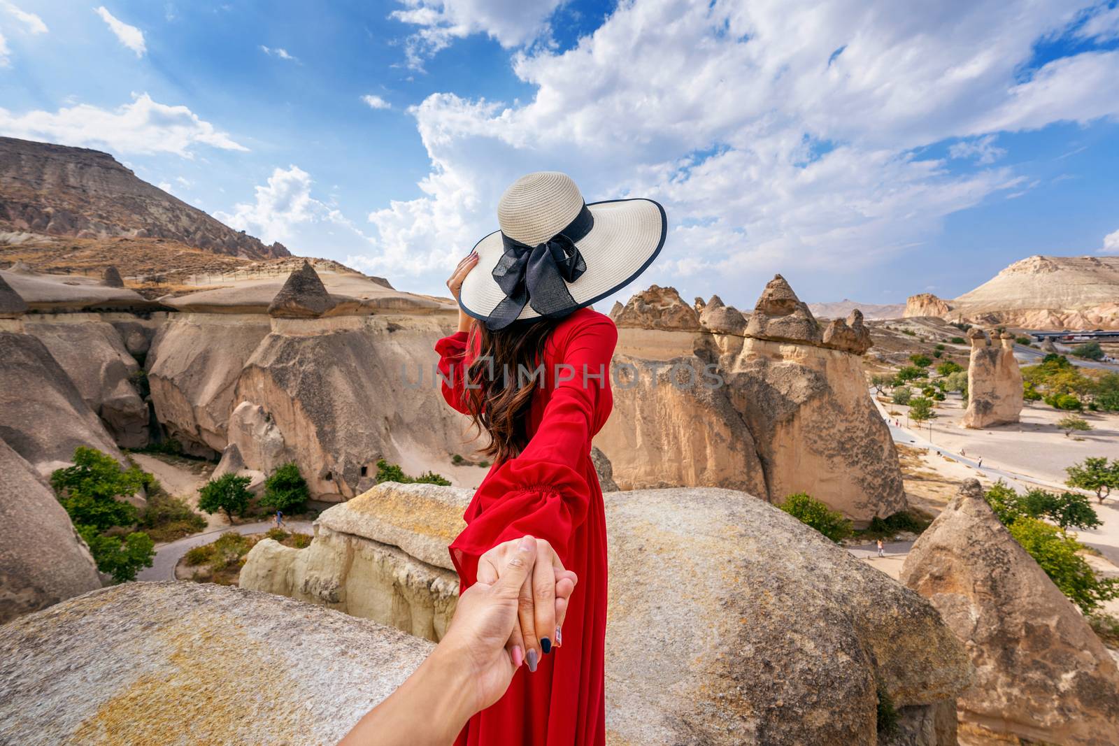 Women tourists holding man's hand and leading him to Fairy Chimneys in Cappadocia, Turkey. by gutarphotoghaphy