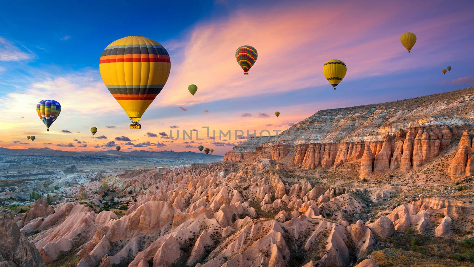 Hot air balloons and Red valley  at sunset in Goreme, Cappadocia in Turkey.