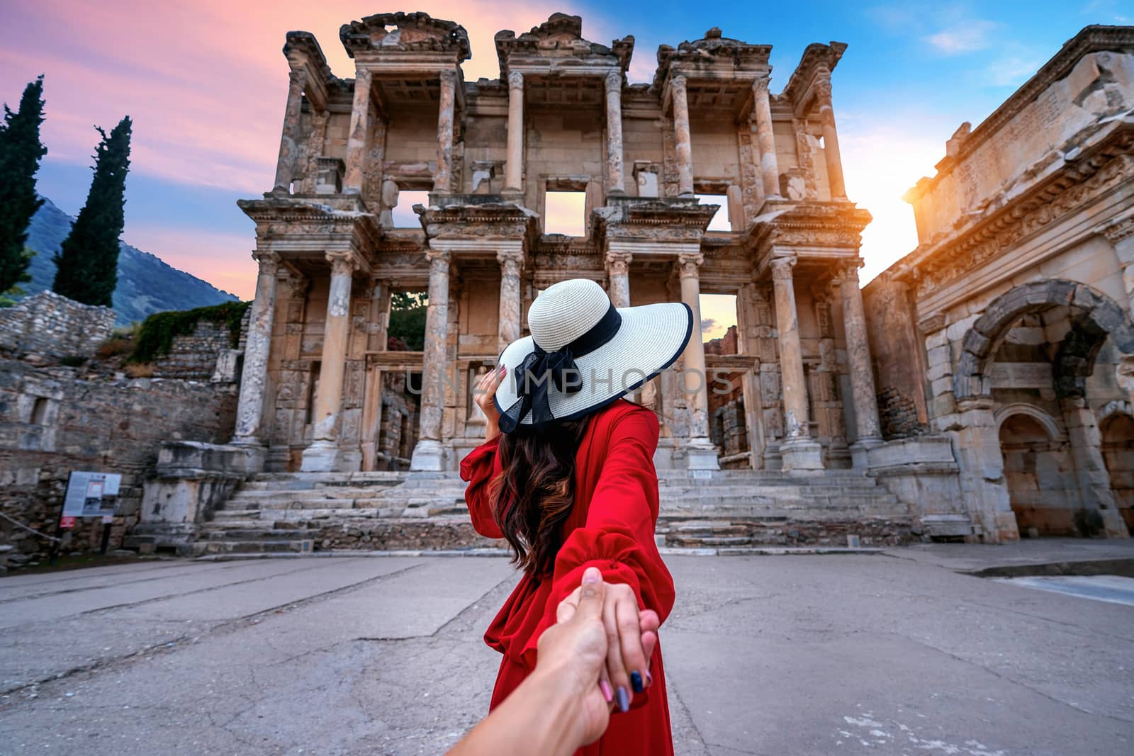 Women tourists holding man's hand and leading him to Celsus Library at Ephesus ancient city in Izmir, Turkey.