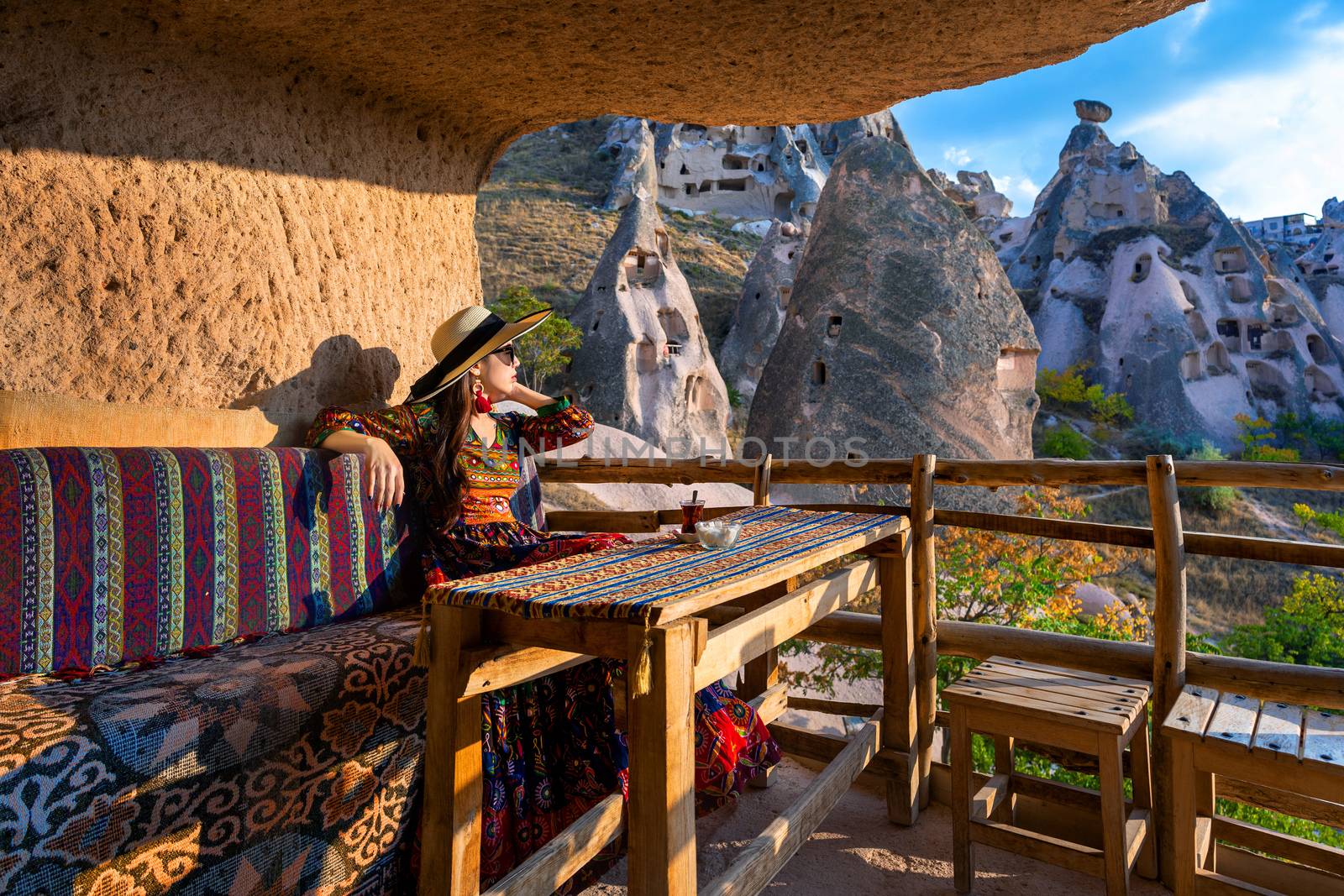 Woman in Bohemian dress sitting on traditional cave house in Cappadocia, Turkey. by gutarphotoghaphy