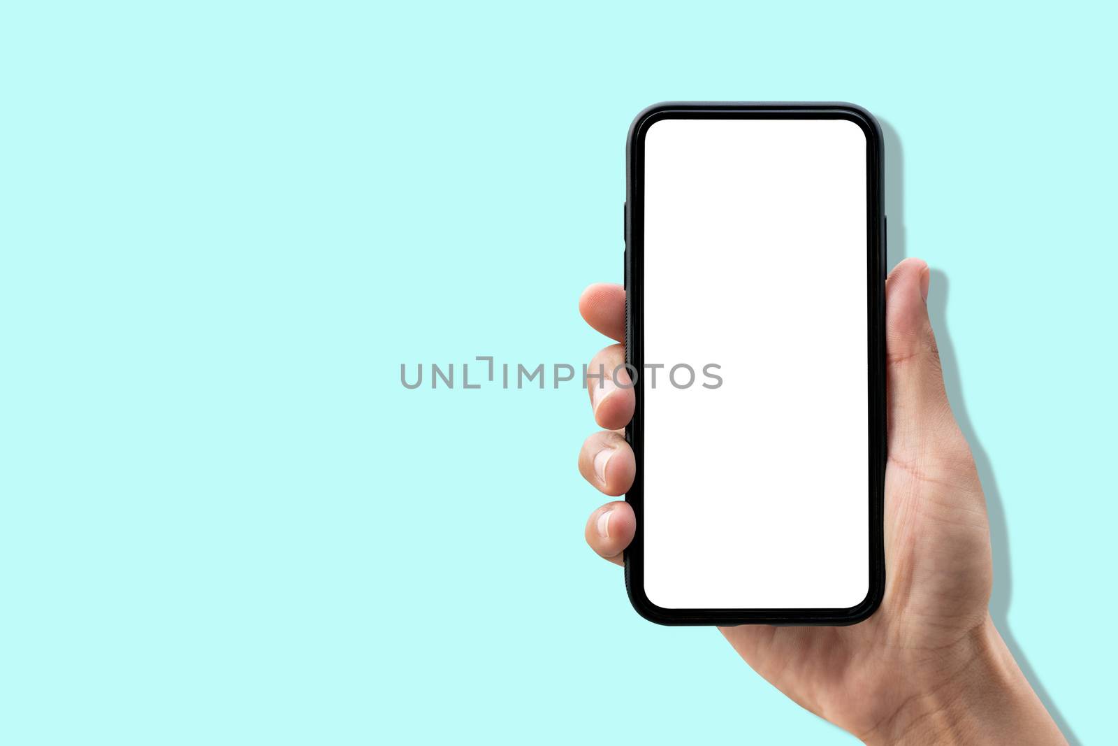 Hand holding smartphone on pastel blue background.