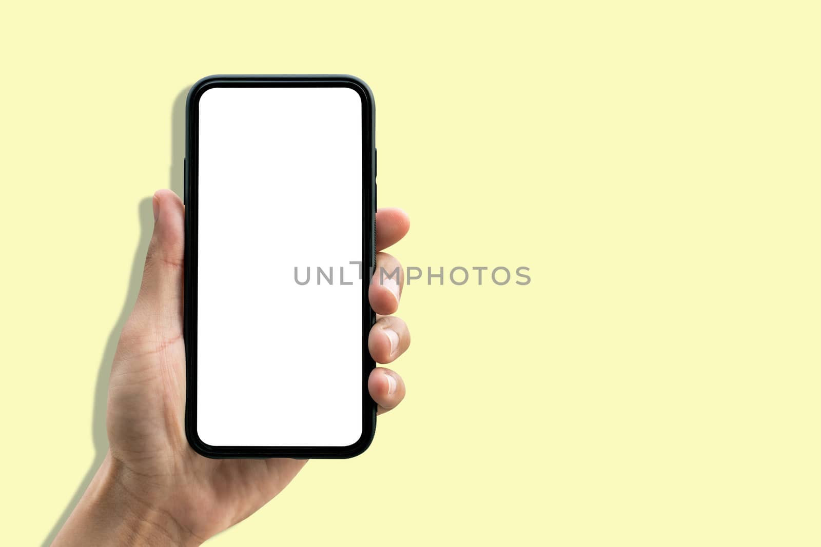 Hand holding smartphone on pastel yellow background. by gutarphotoghaphy