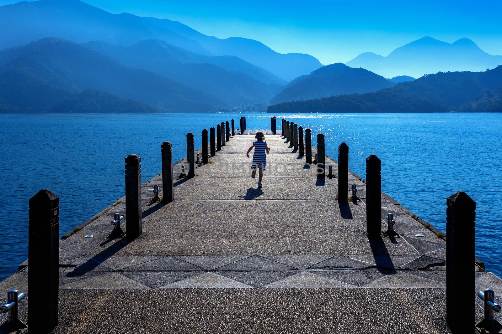 Little girl running on pathway in Sun moon lake, Taiwan. by gutarphotoghaphy