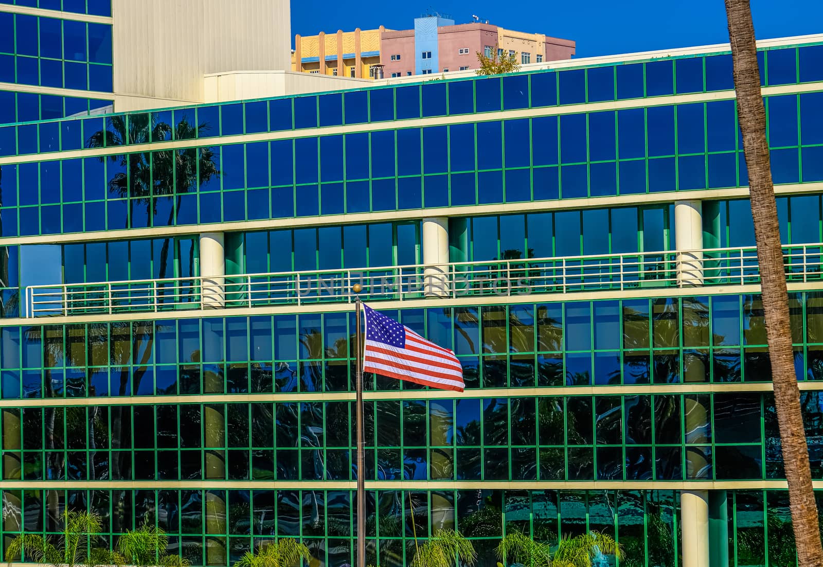 American Flag by Blue Glass Building in Tropical Setting