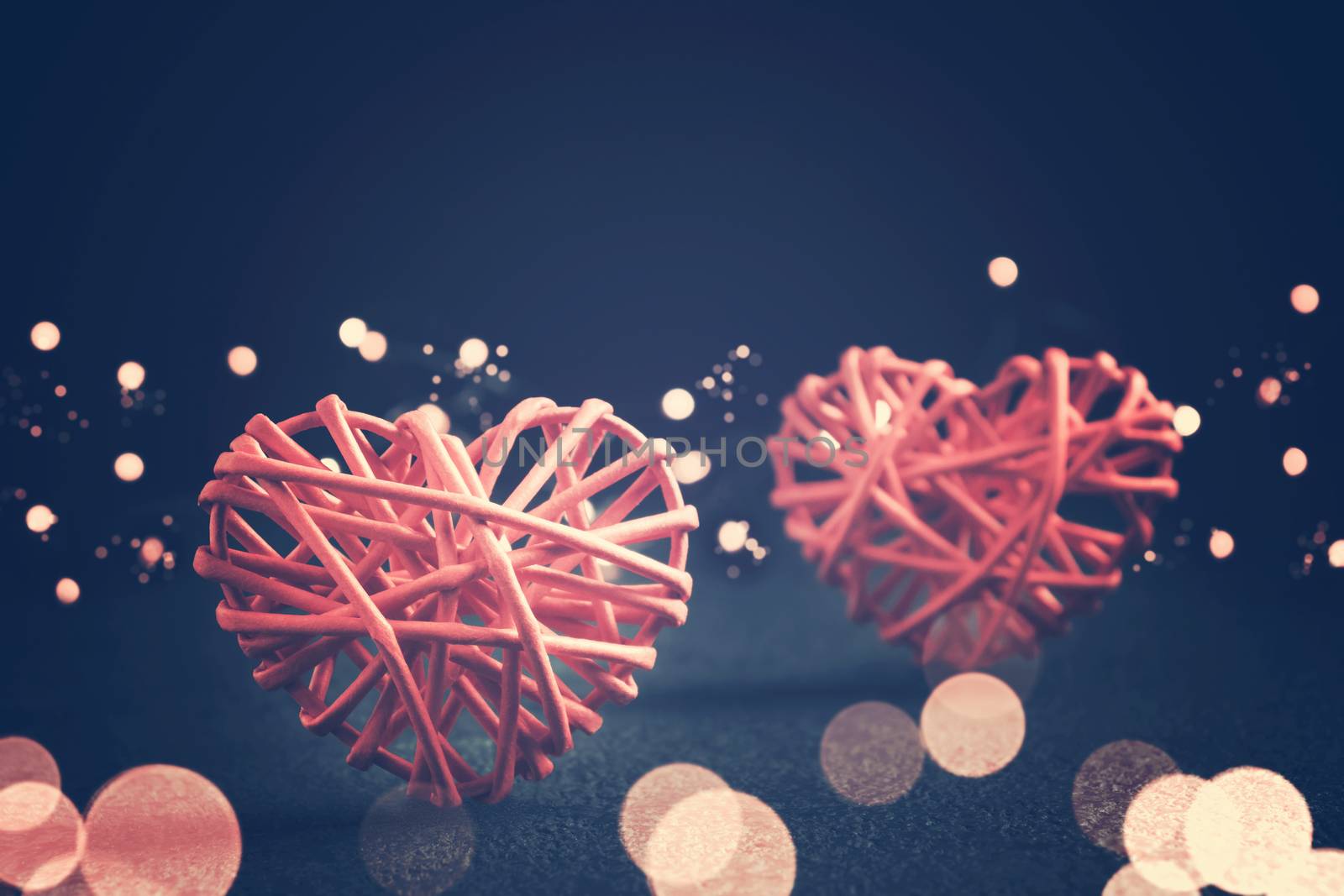 Romantic composition - two wicker hearts symbol of love and lights on a dark table. Valentines day concept by galsand