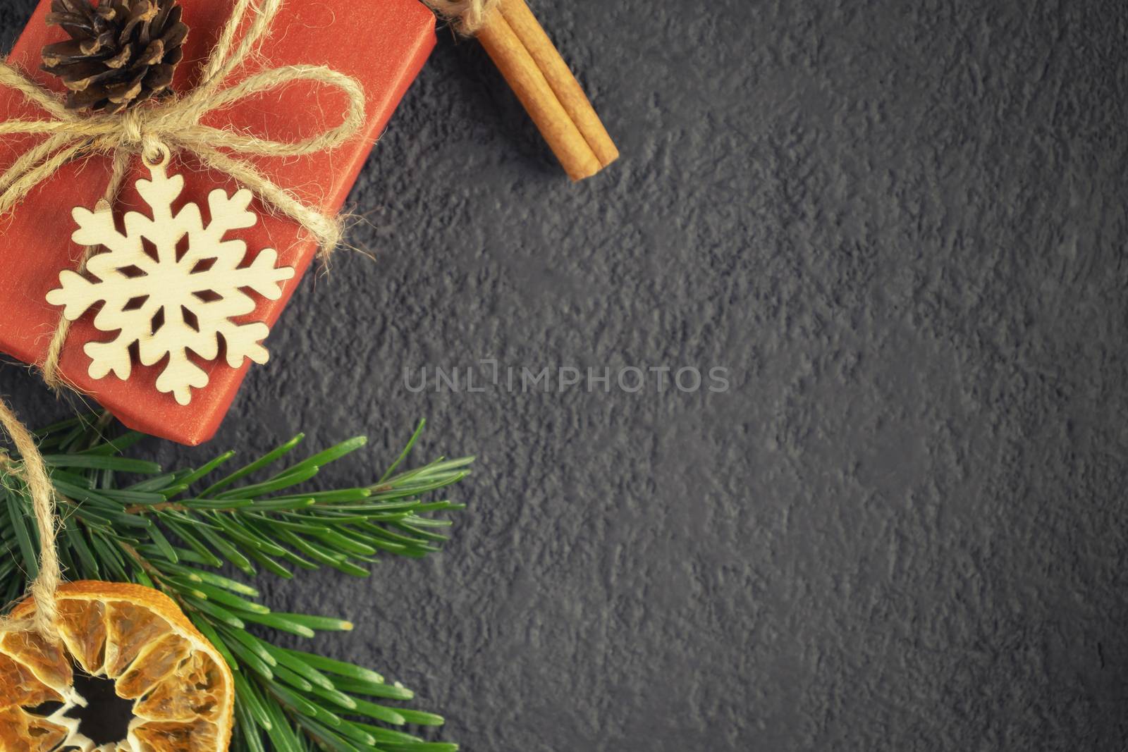 Christmas or New Year dark background with decorations from natural materials - Christmas tree twigs, cinnamon and dried orange.