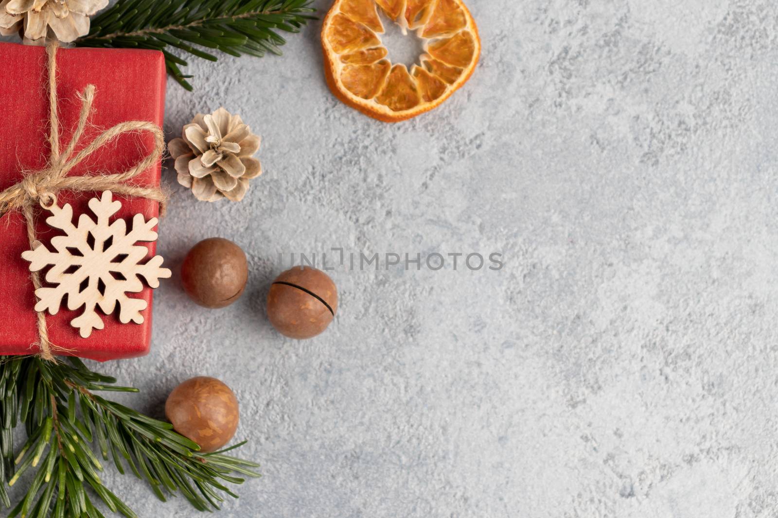 Christmas or New Year gray background with decorations from natural materials - Christmas tree twigs, nuts, cones, wooden snowflake and dried orange.