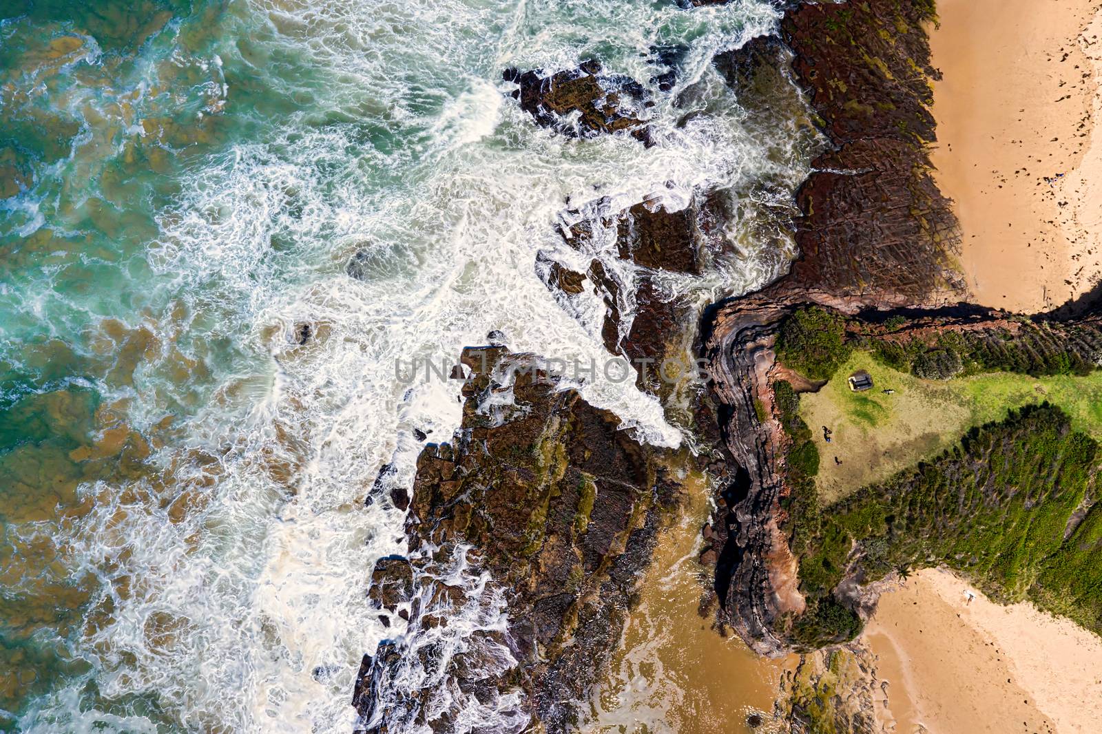 Aerial views over the steep headland to the rocky shores and beach below by lovleah