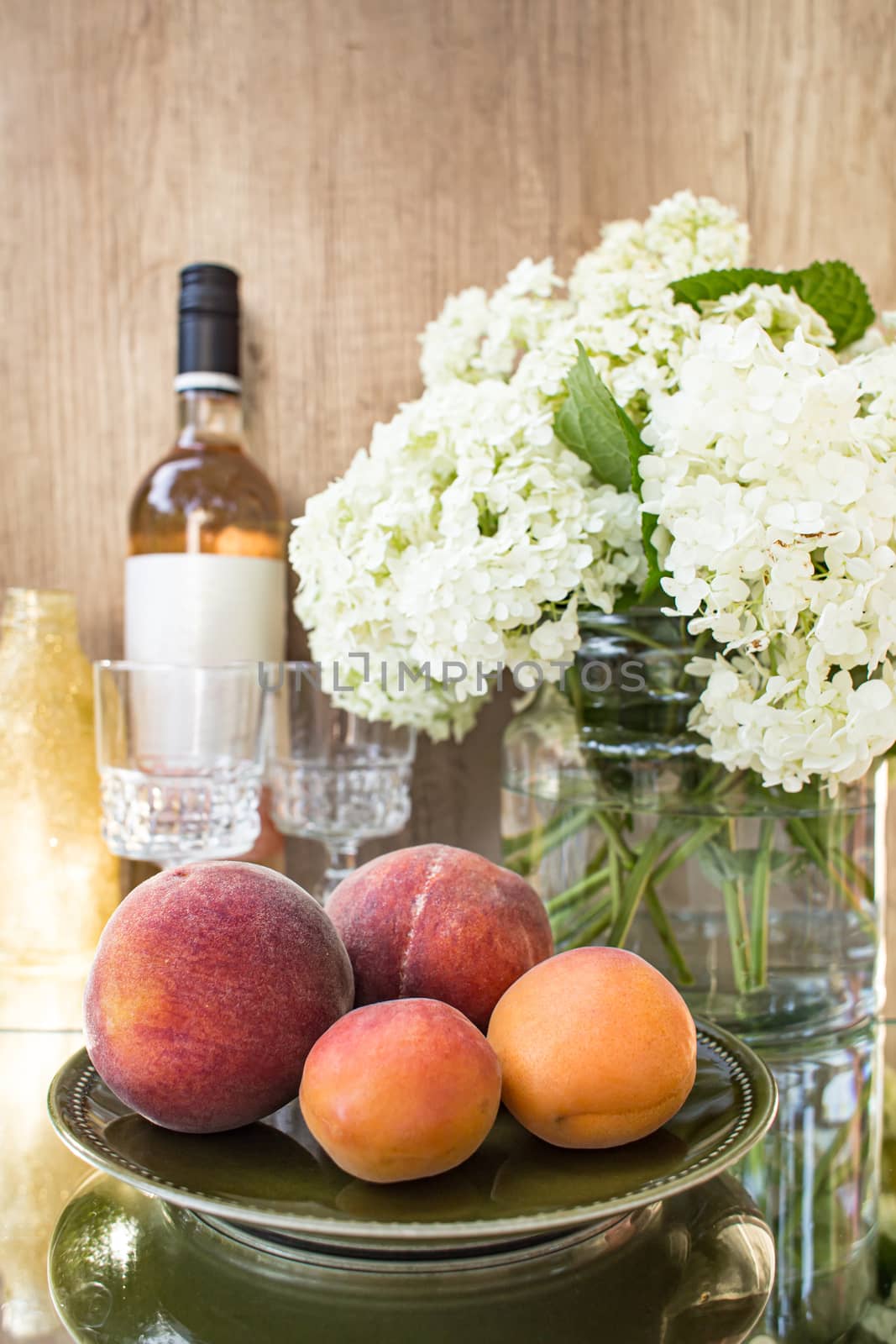 Rose wine in glasses. Rose wine on golden bottles background with flowers and fruits