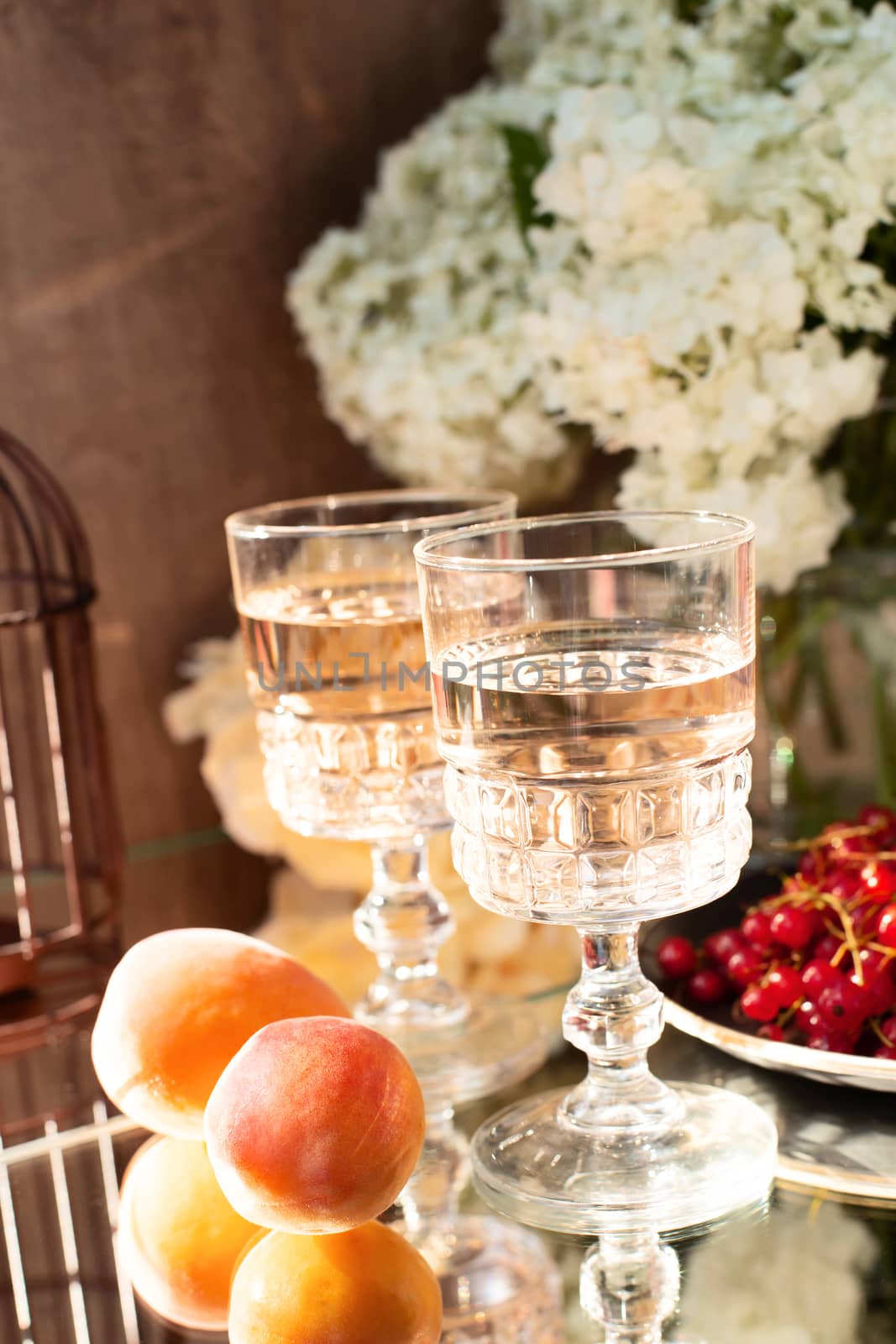 Rose wine in glasses. Rose wine on golden bottles background with flowers and fruits