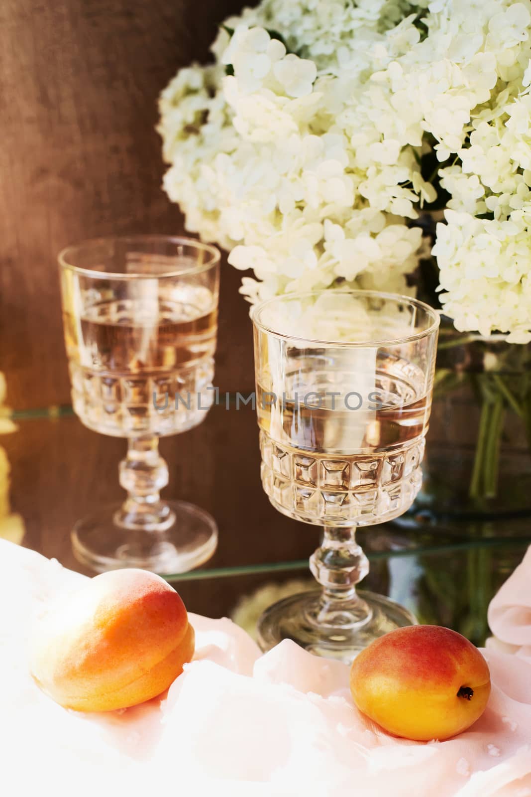 Rose wine in glasses. Rose wine on golden bottles background with flowers and fruits