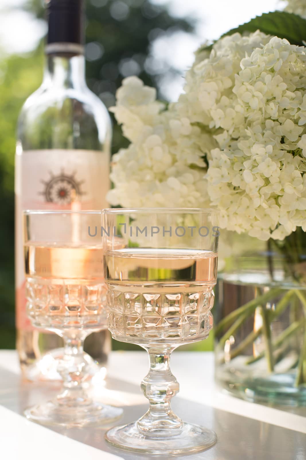 Rose blush wine in glasses. Bottle of rose wine with flowers on background. Prosecco.