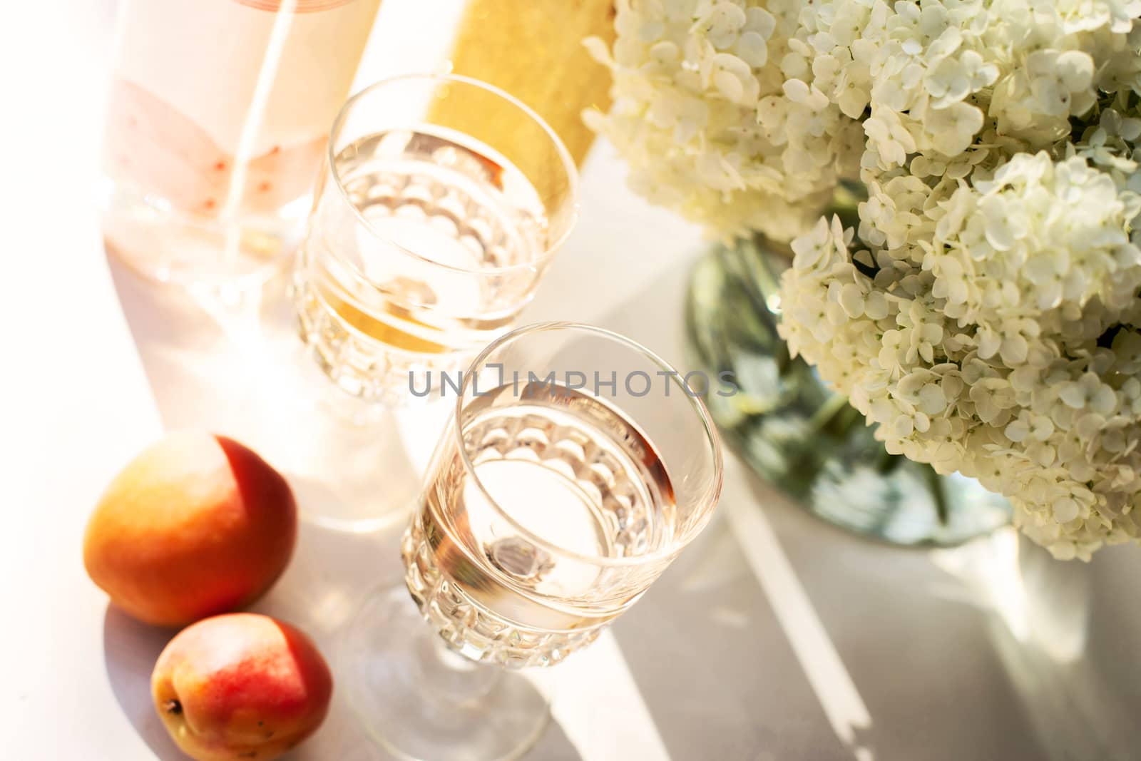 Rose wine in glasses. Rose wine on golden bottles background with flowers and fruits