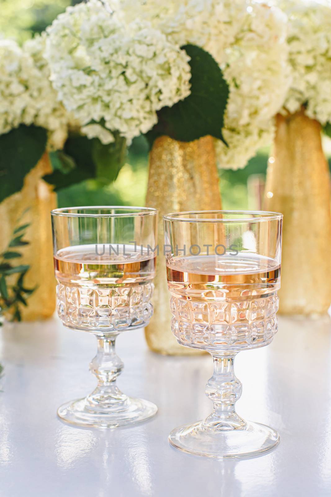 Rose wine in glasses. Rose wine on golden bottles background with flowers