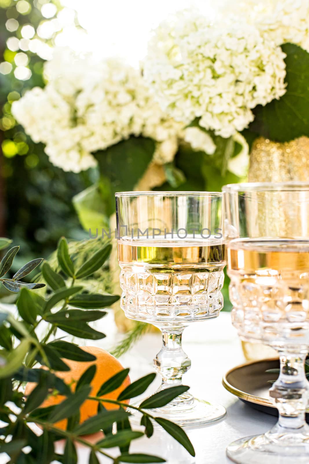 Rose wine in glasses. Rose wine on golden bottles background with flowers and fruits