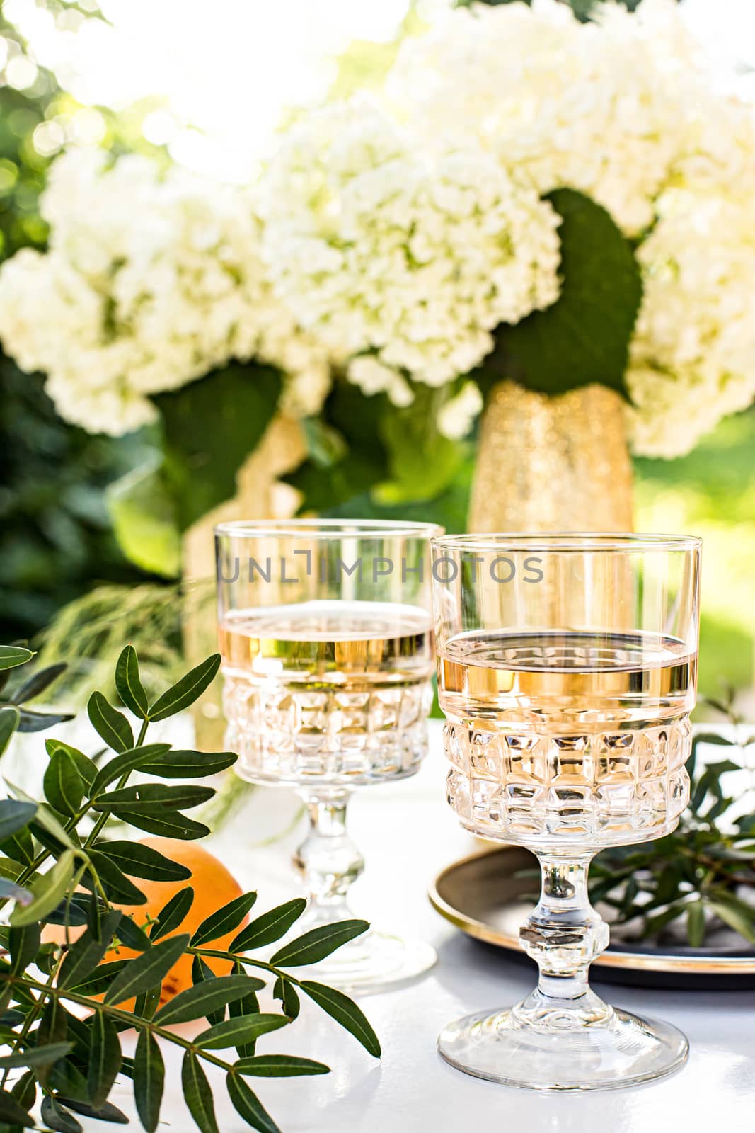 Rose wine in glasses. Rose wine on golden bottles background with flowers and fruits