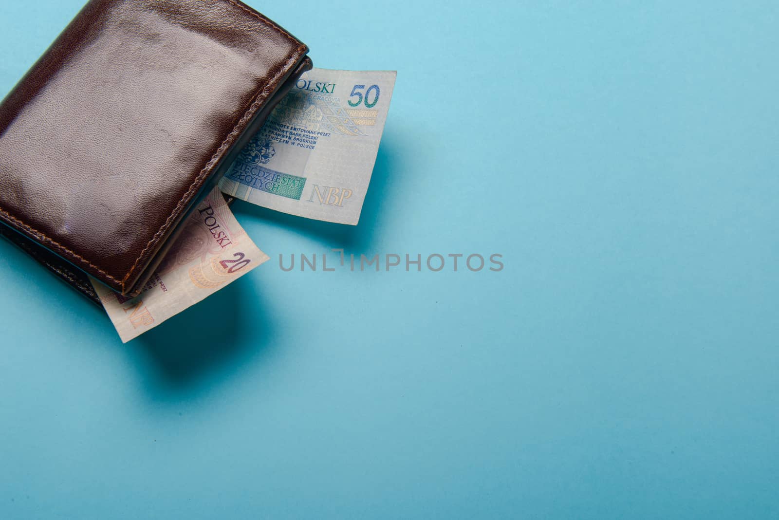 brown mans leather wallet with money bills on a blue background