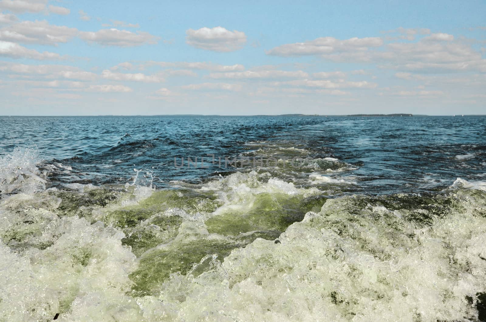 Wake behind motor boat. Big lake in north of Poland. Mikolajki city on horizon.