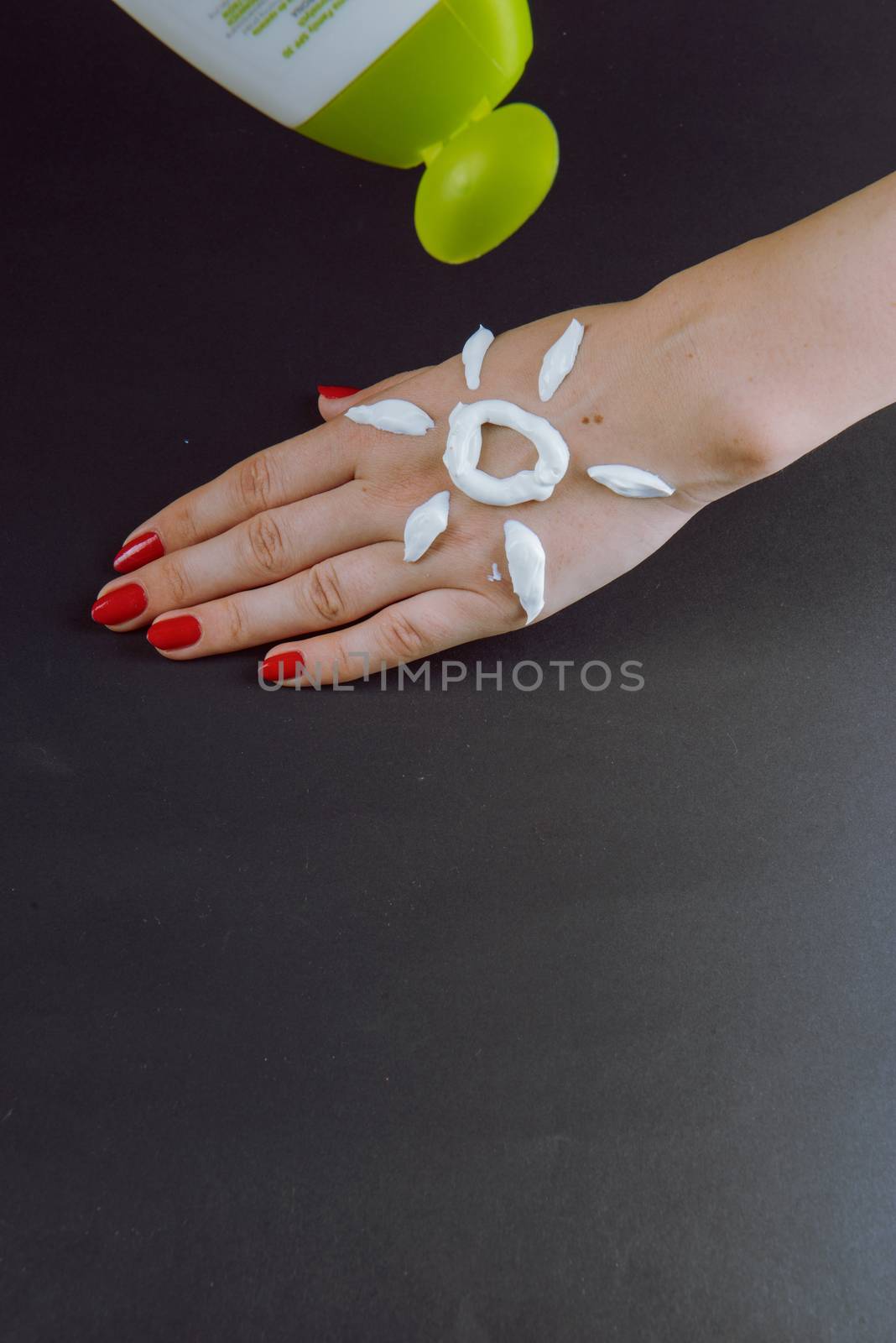 woman applying sunscreen cream on Hand. Red nails.