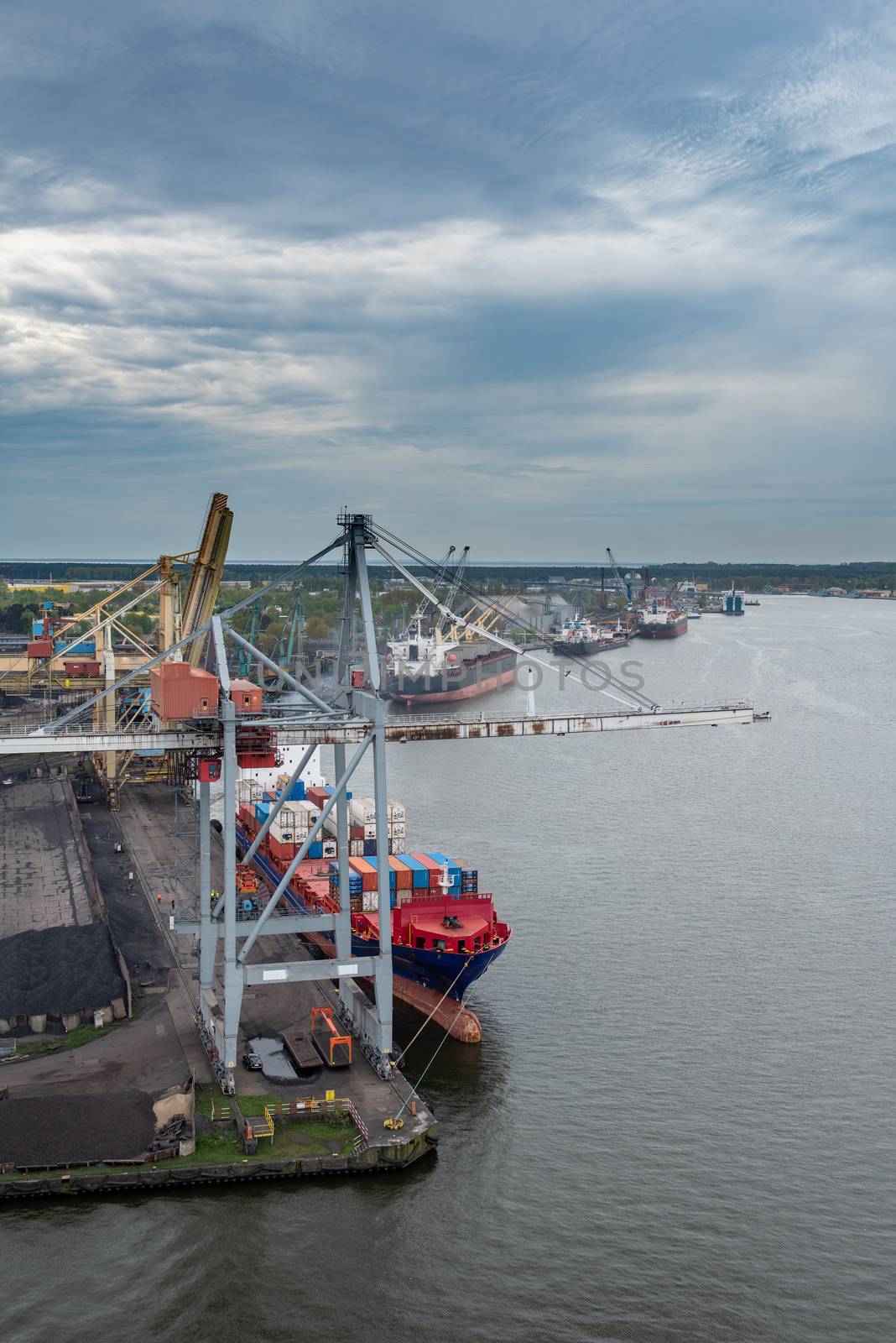 Container ship in export and import business and logistics. Shipping cargo to harbor by crane. Water transport International.