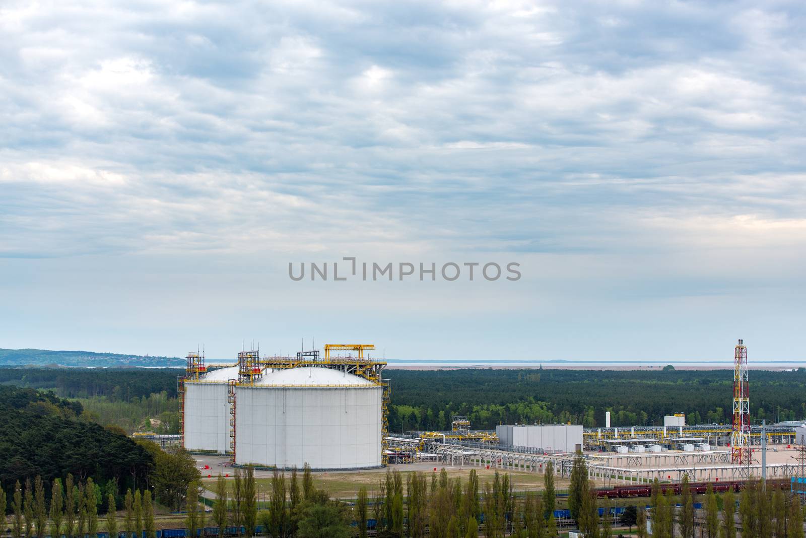 Large industrial tanks for petrochemical plant, oil and gas fuel or water in refinery or power plant for industrial plant on blue sky background. LNG terminal in Swinoujscie, Poland.