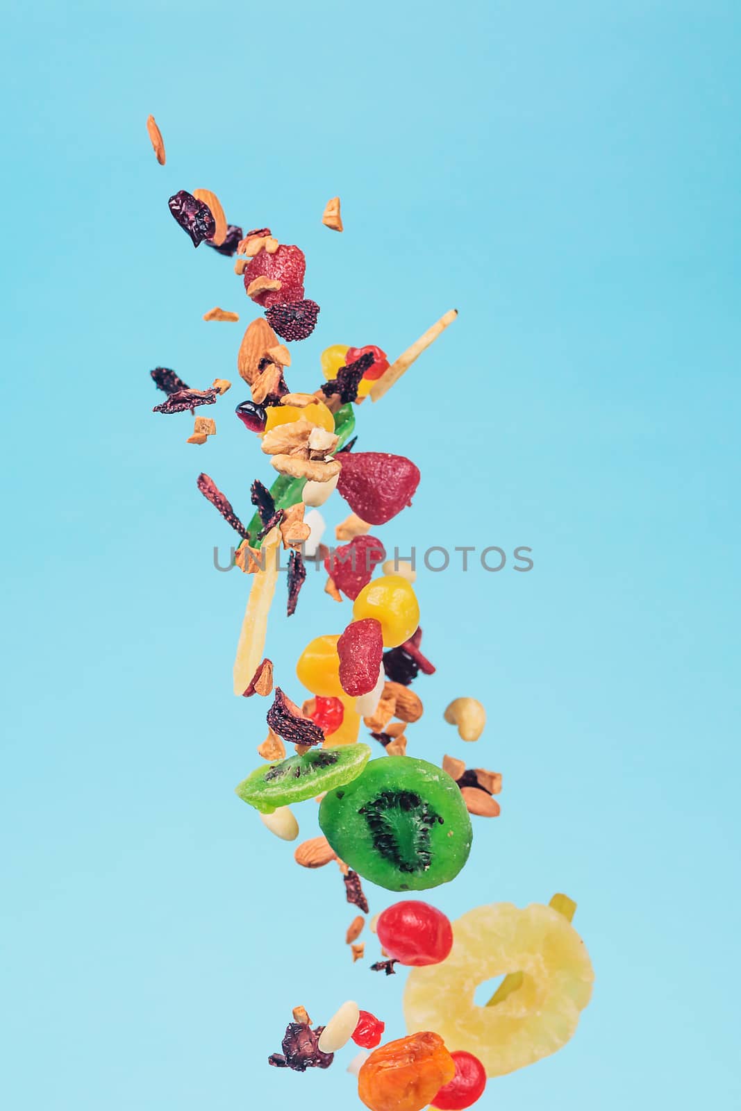 Dried and candied fruits and nuts flying on blue background. Stock photo of healty and nutrient food. Conceptual photo of vegan and vegetarian healty food.