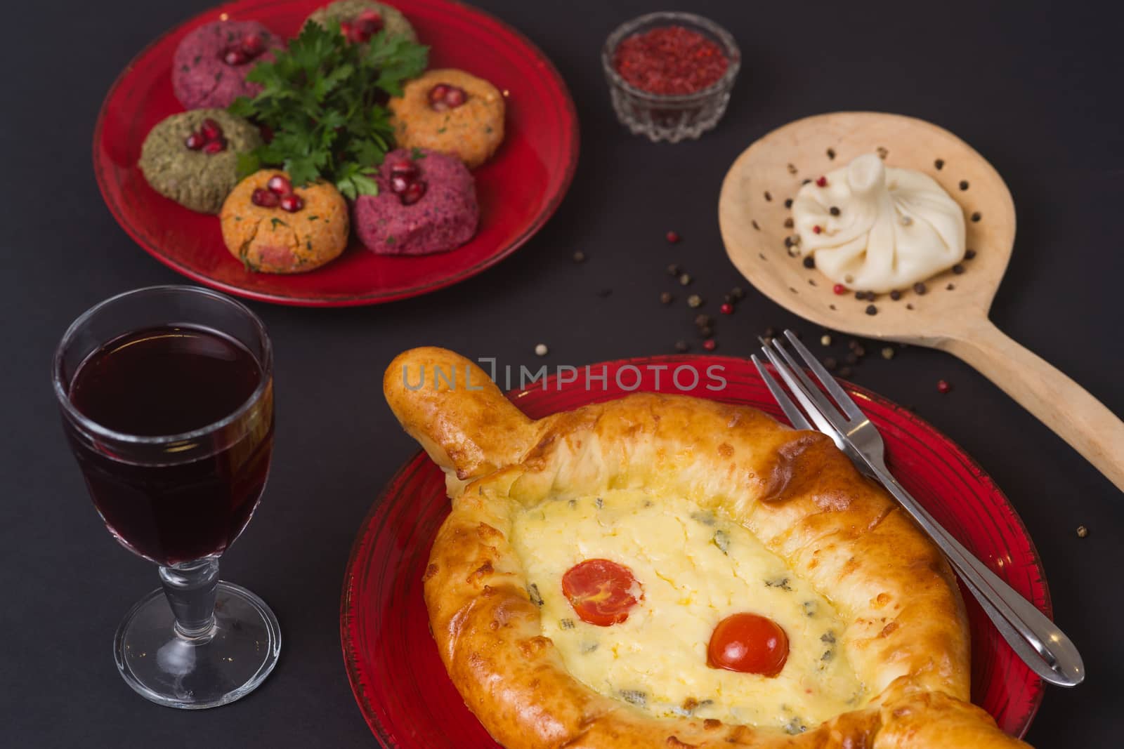 Georgian food on black table. khinkali, phali,  khachapuri with tomatos, adjika and glass of red wine.