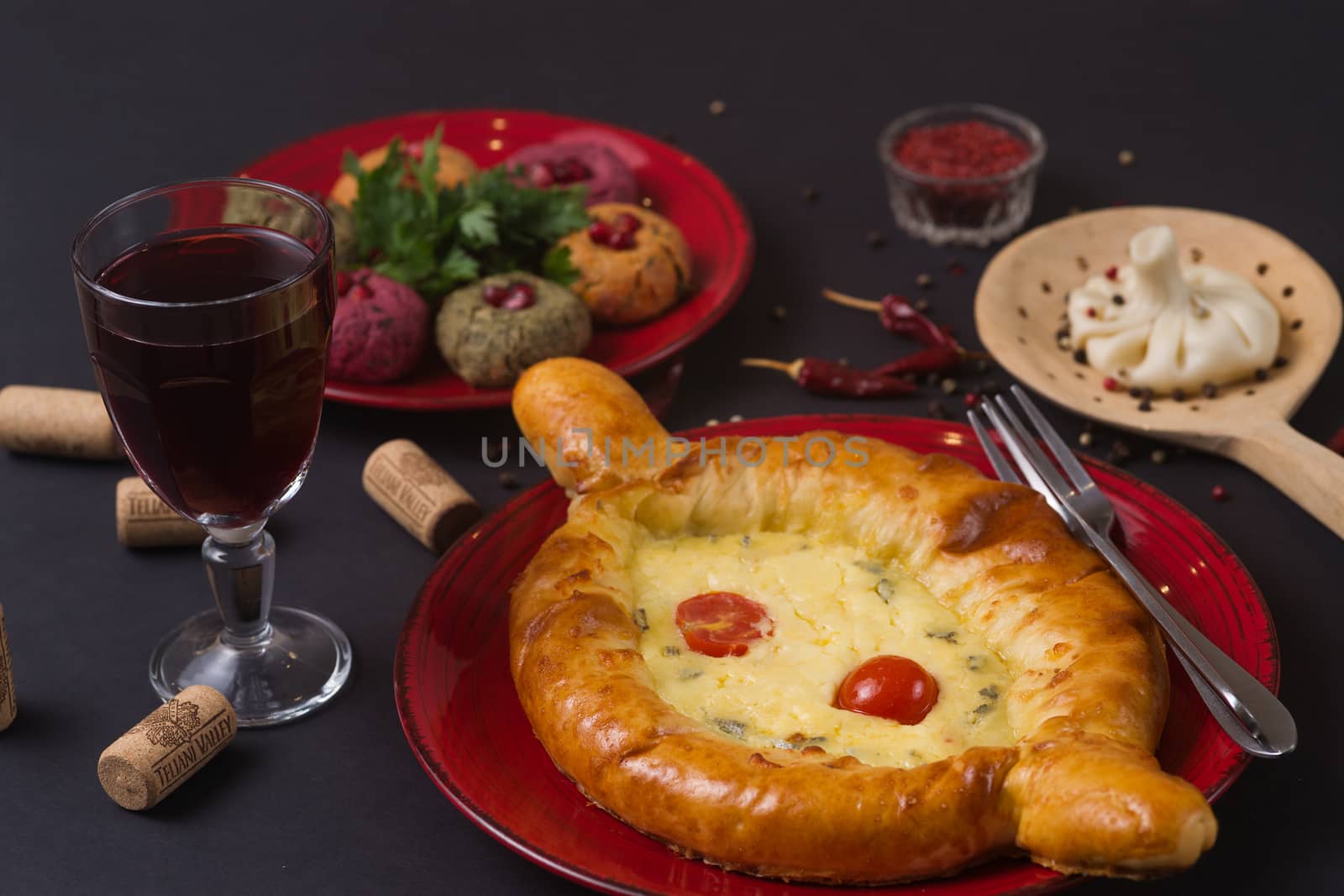 Georgian food on black table. khinkali, phali,  khachapuri with tomatos, adjika and a glass of wine.