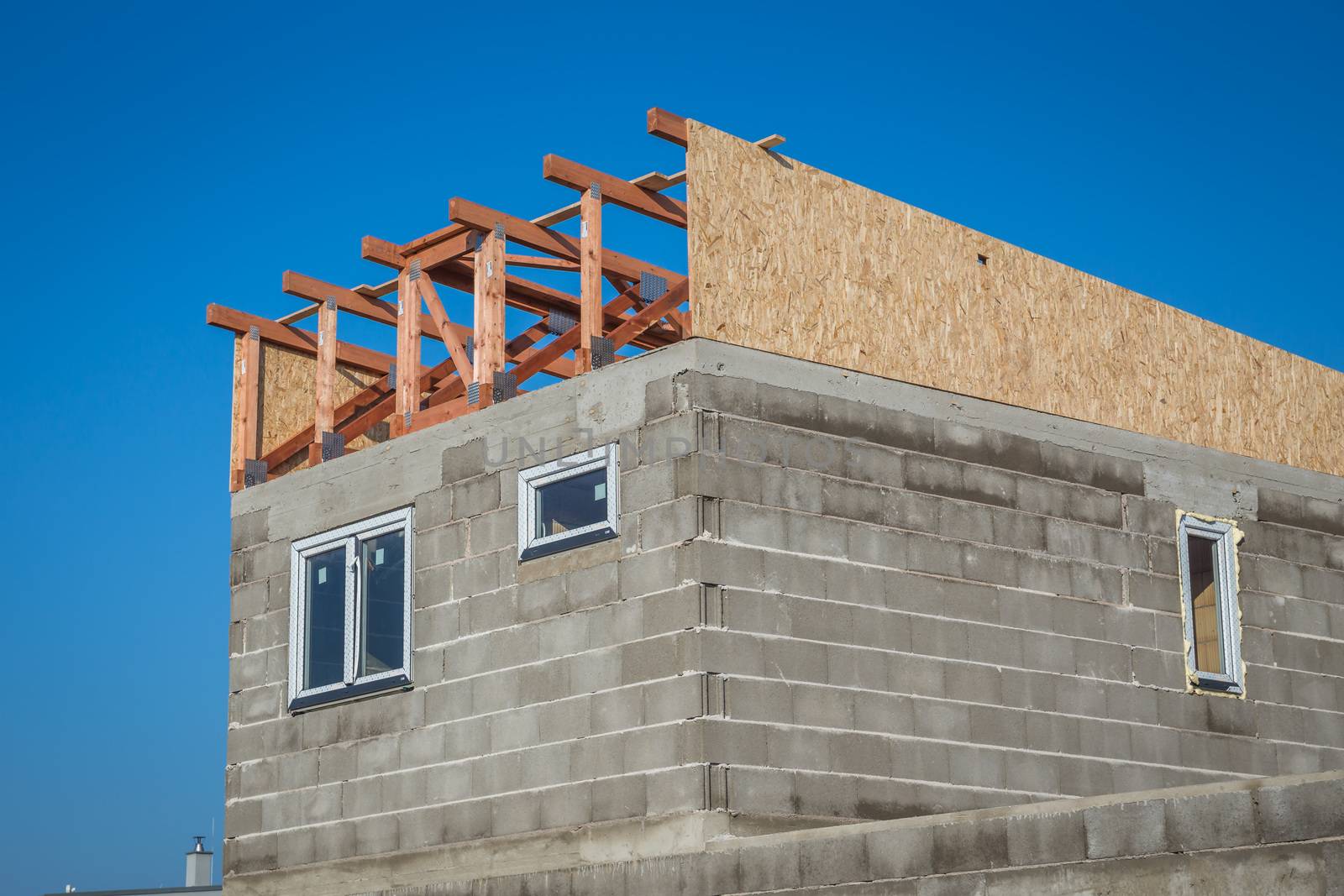 Roof construction - installation of wooden beams at house construction site. Building details with wood, timber and metal holders by petrsvoboda91