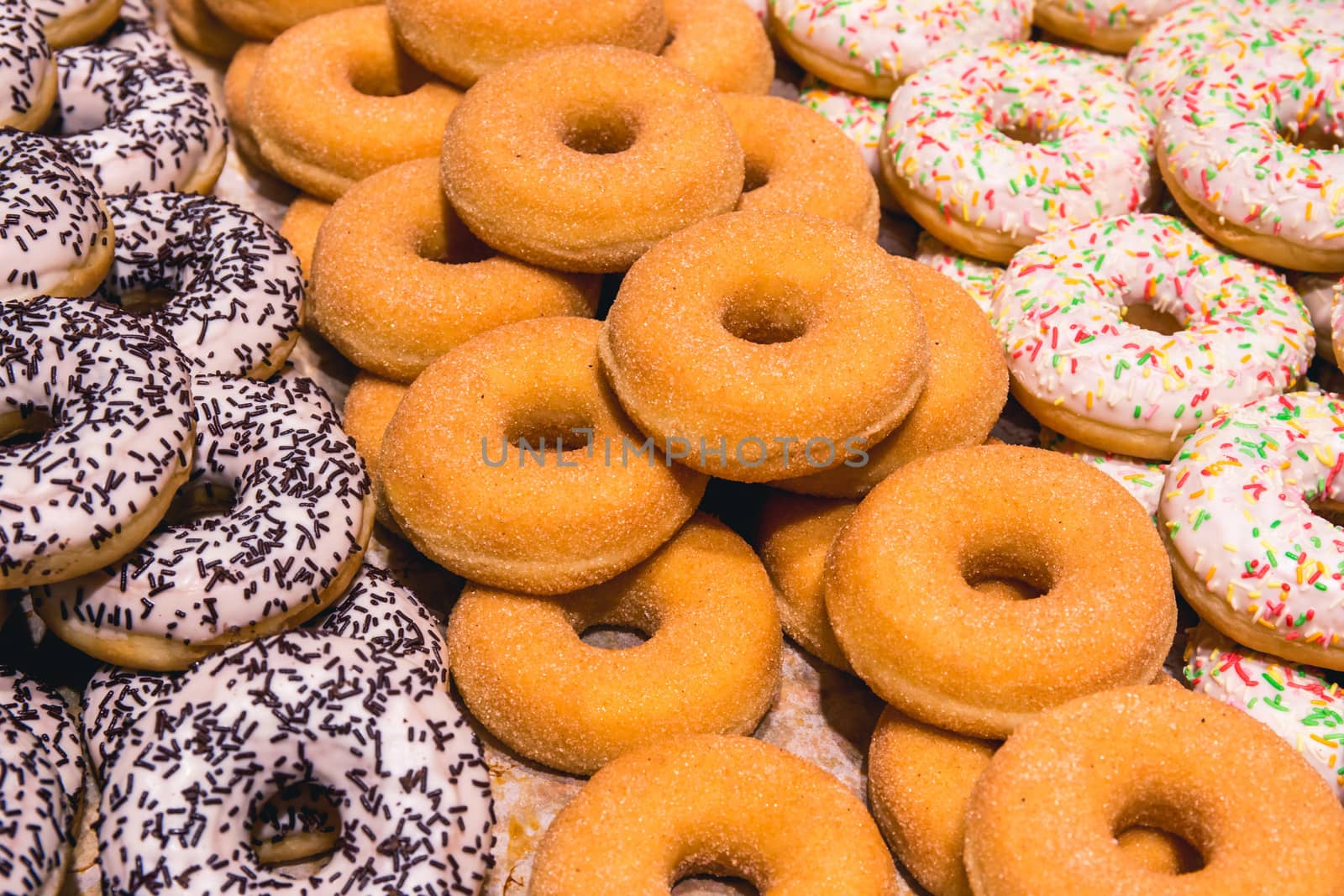 Background texture: sweet dessert. Delicious pastries on the shelf of a candy store. Donuts with holes inside.